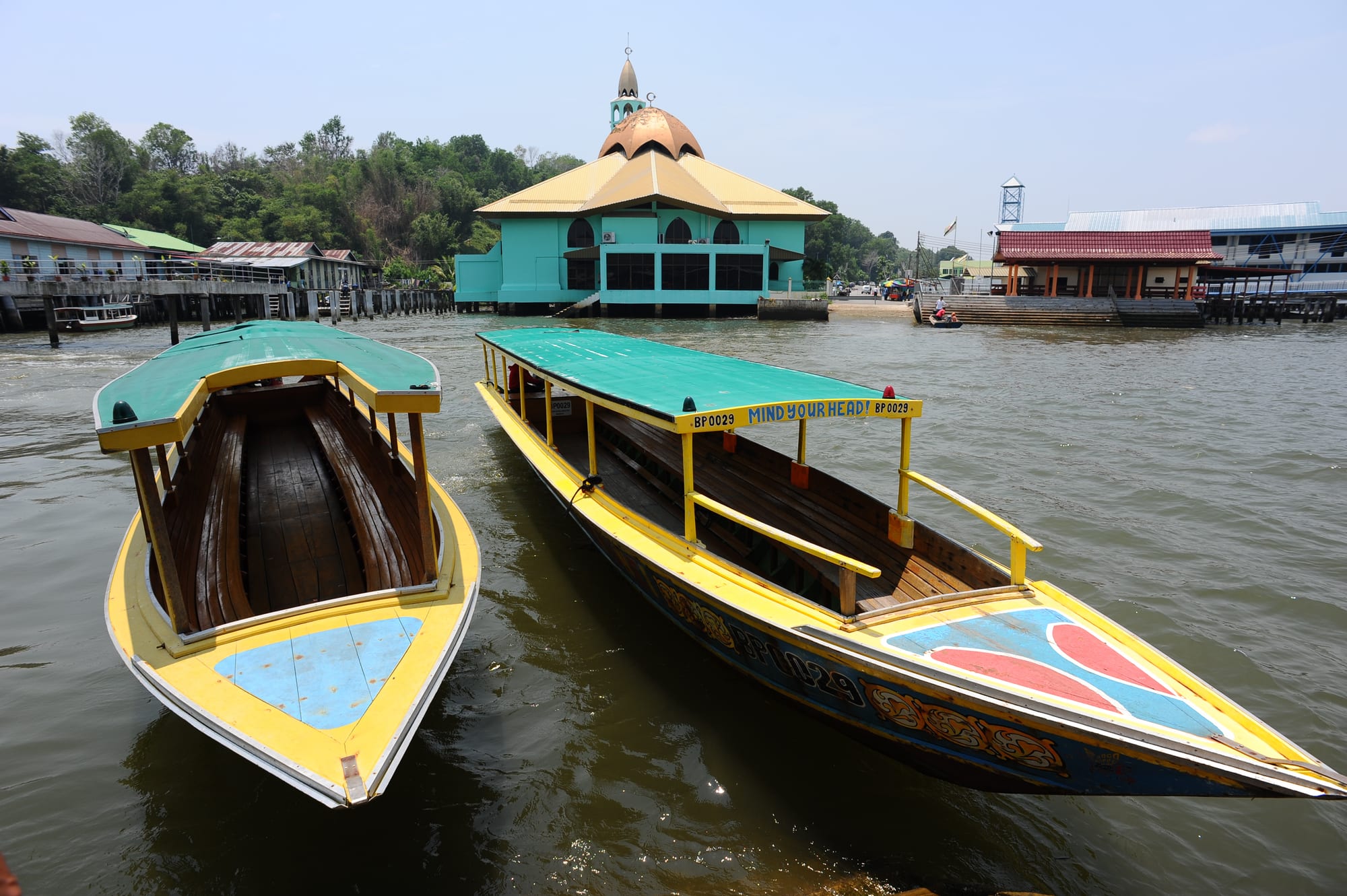 Wooden houses and a mosque on stilts stretching along a river, linked by plank walkways
