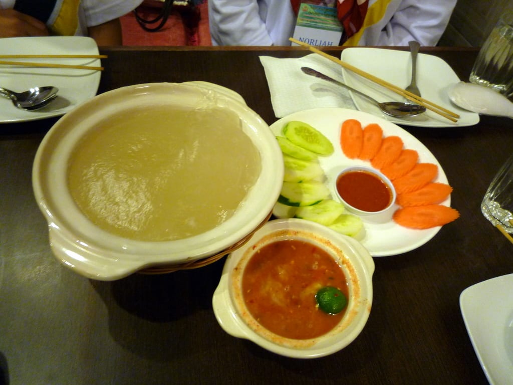 A bowl of thick, pale, glue-like starch paste beside small dishes of sauce and side dishes