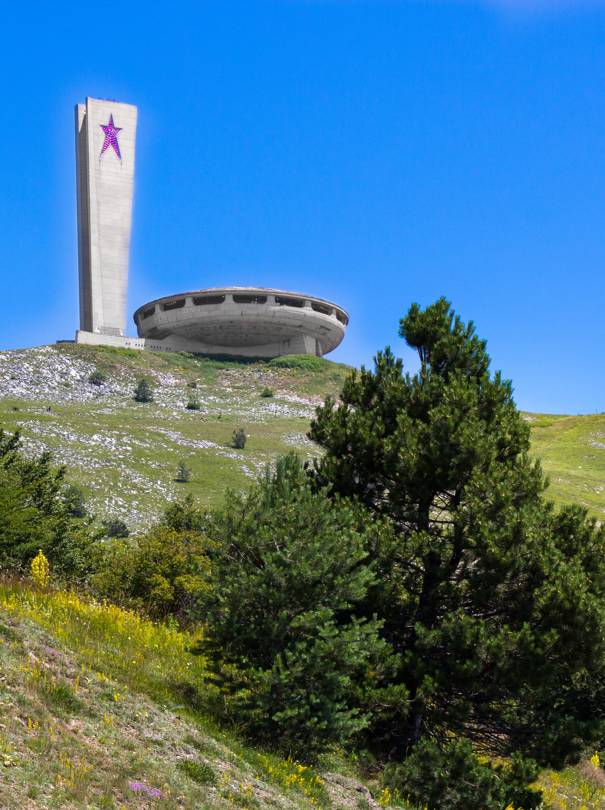 A huge concrete flying-saucer-shaped building with a tall tower, abandoned on a bare mountaintop
