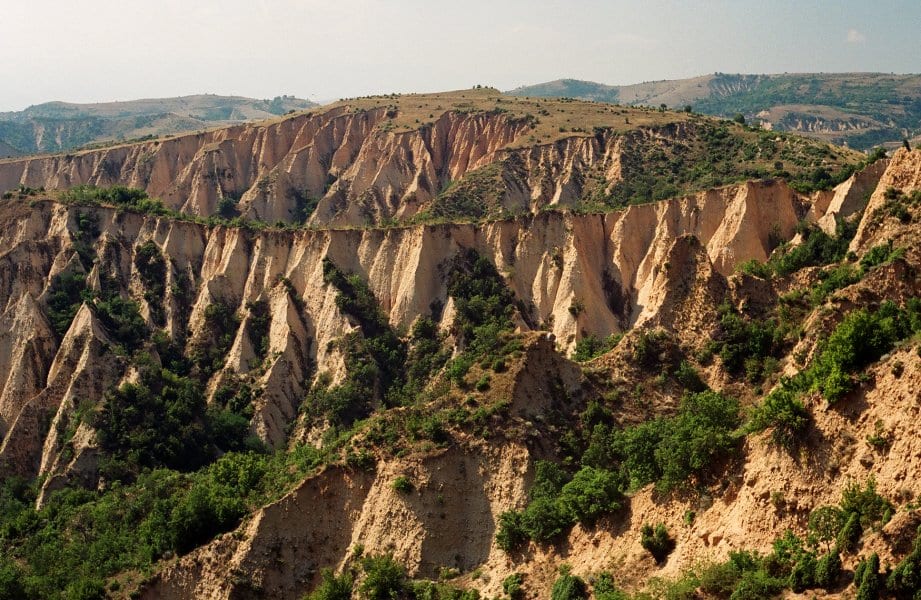Bare, pale, fluted sandstone cliffs and pinnacles rising above a small red-roofed town