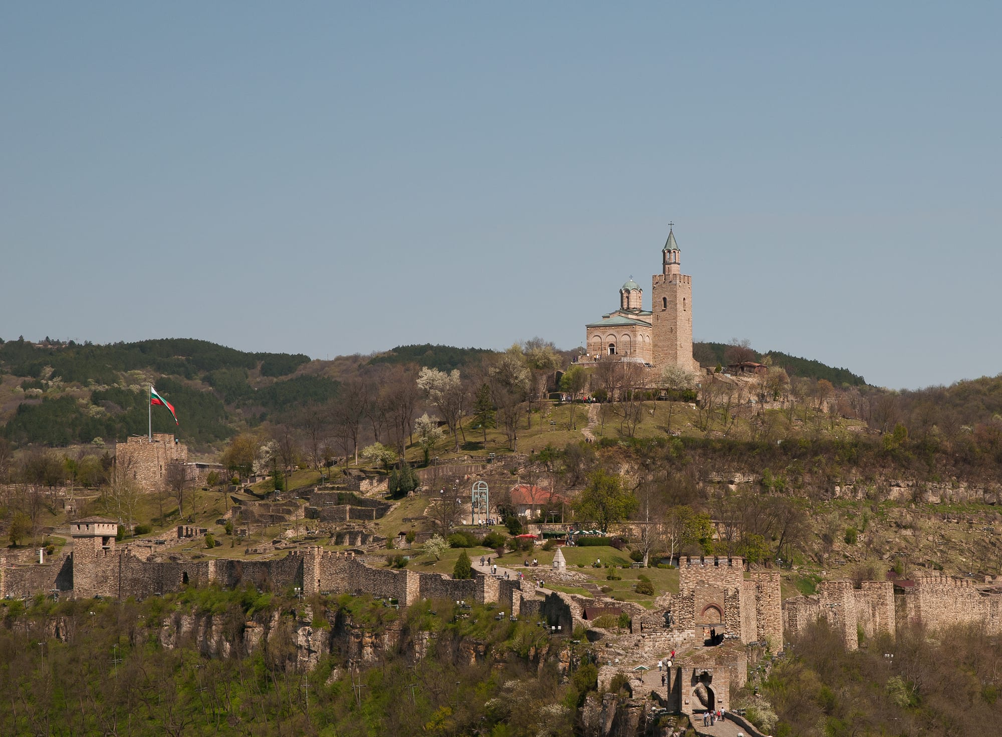 A fortified hill wrapped in a river bend, ramparts climbing to a church on the summit
