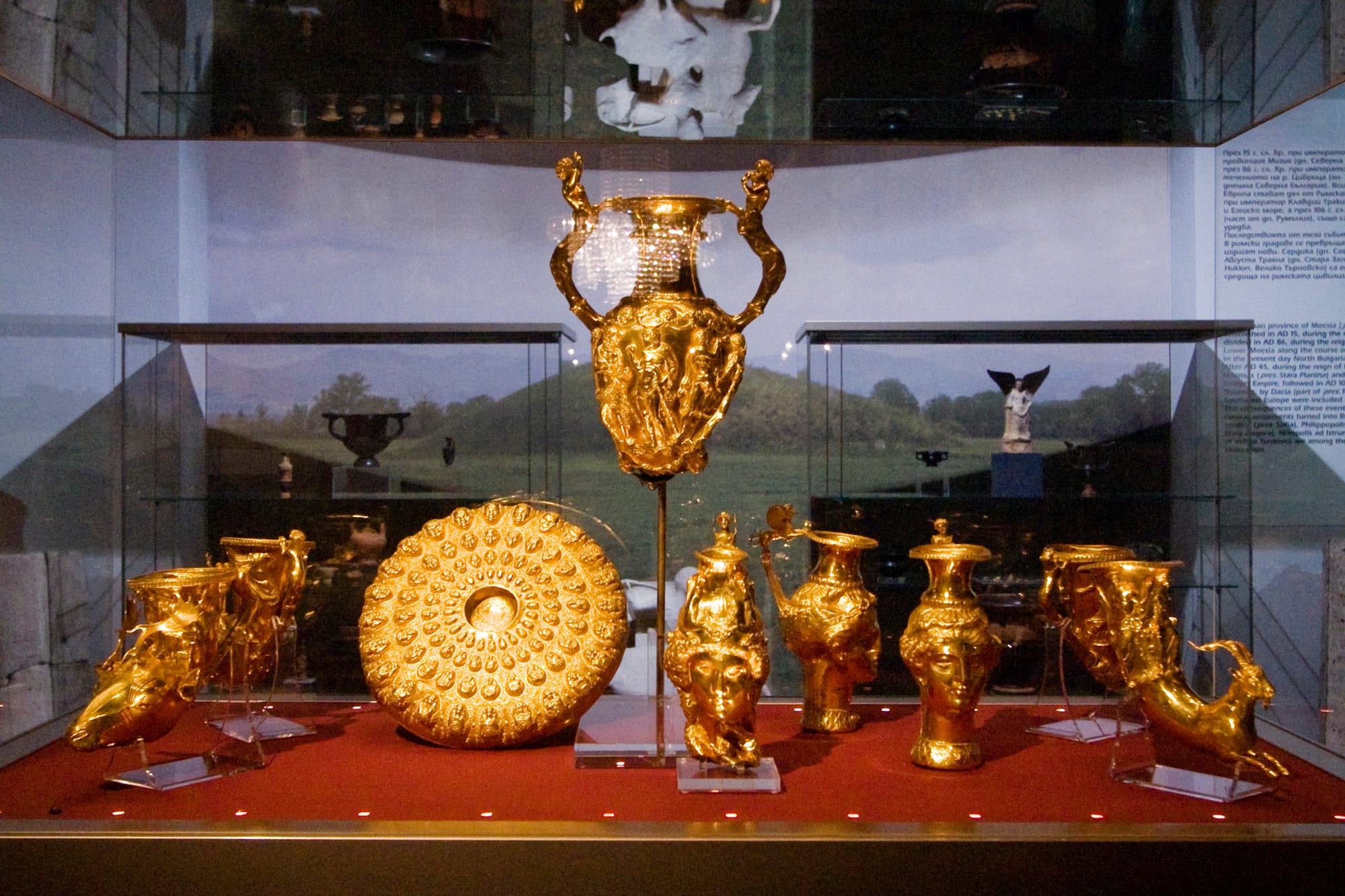 A set of ornate ancient gold drinking vessels shaped as animal heads and a woman's head, on a dark background