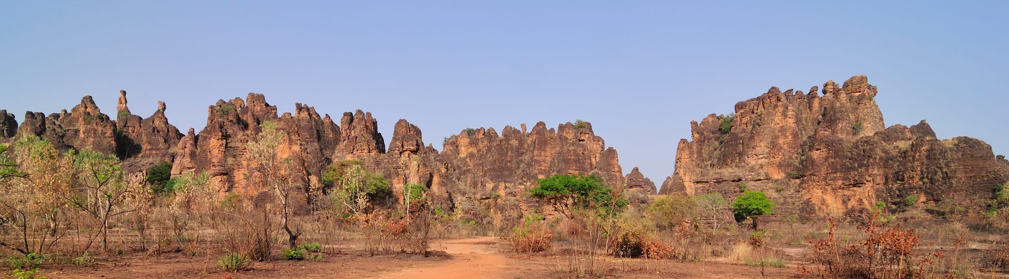 A row of narrow, jagged sandstone spires and fins rising from dry scrubland