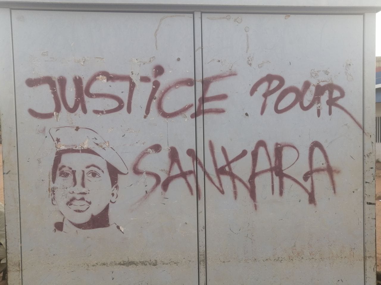 A colourful street mural of Thomas Sankara in a beret, with a raised fist and slogans in French