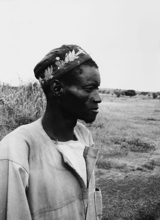 An early photographic portrait of a Mossi chief in a robe and cap, seated formally