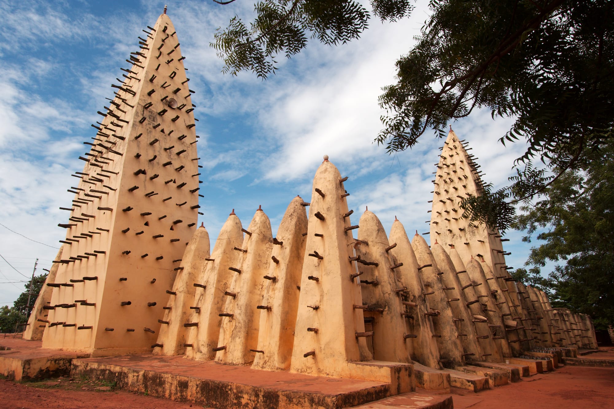 A mud-brick mosque bristling with wooden scaffolding beams and tapering pinnacled towers