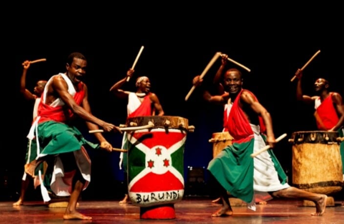 Drummers in traditional dress performing with large drums balanced on their heads