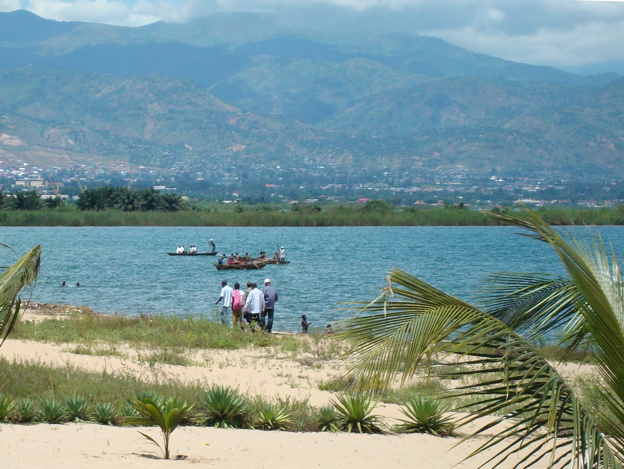 A wide blue lake meeting green hills, a low city spread along the near shore
