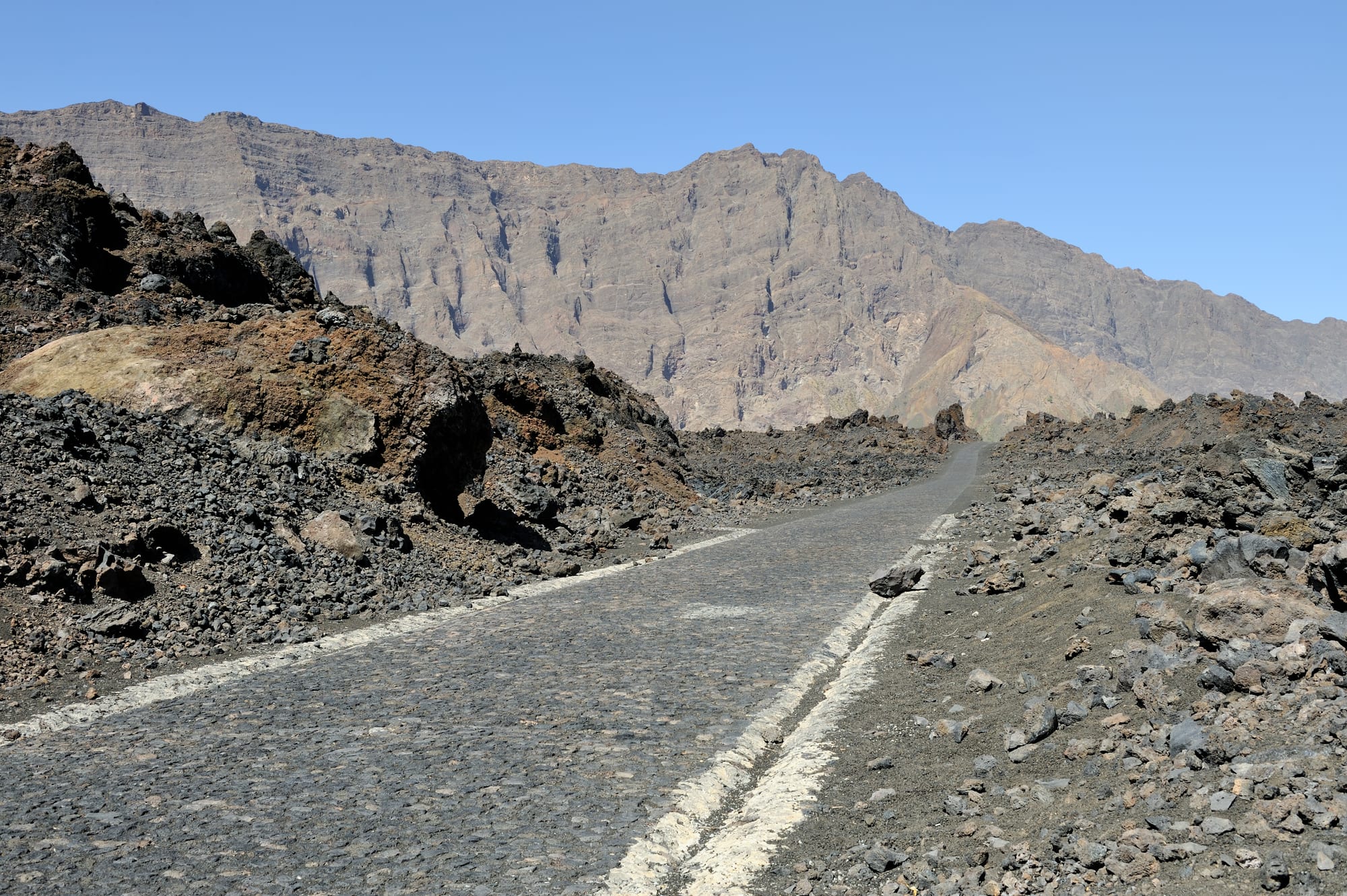 A perfect black volcanic cone rising above a lava plain and a small village of low houses