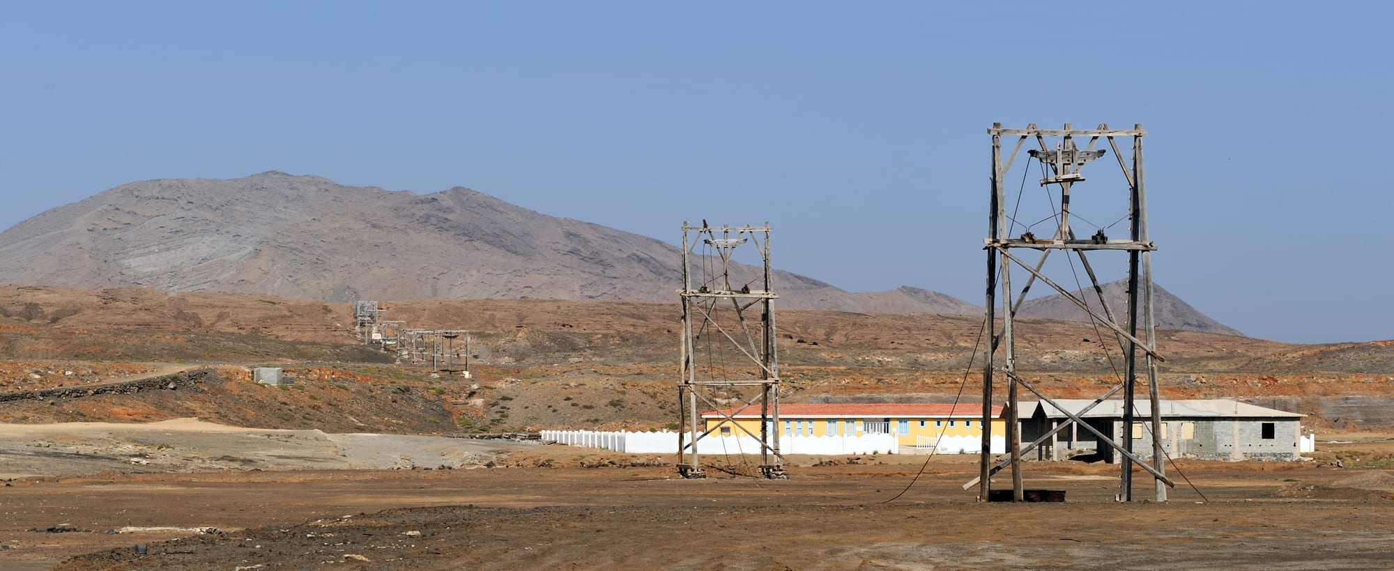 A salt lake in the flat floor of an old volcanic crater, with rusting cable-car towers