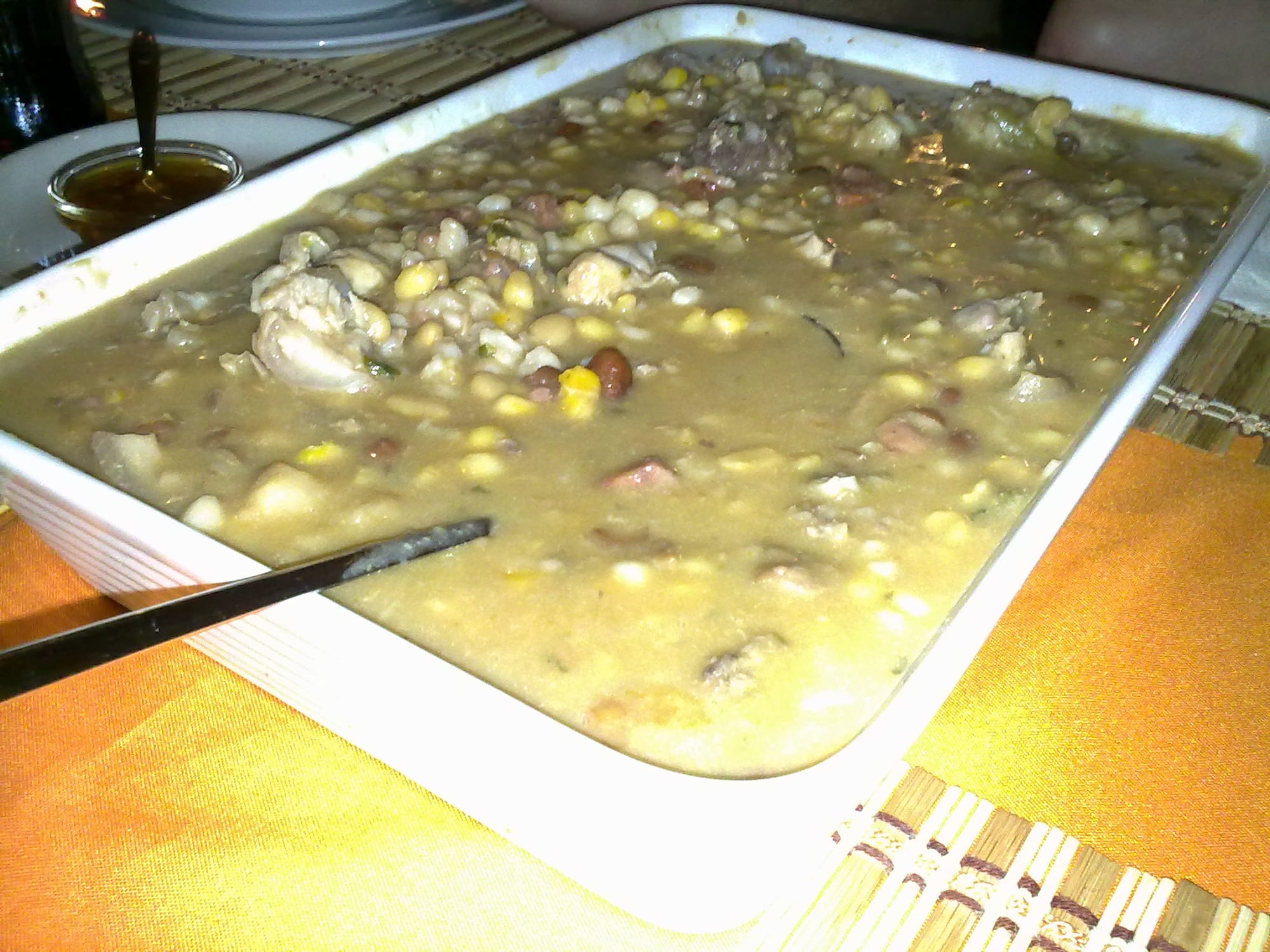 A bowl of corn, beans, meat and vegetables in a thick stew