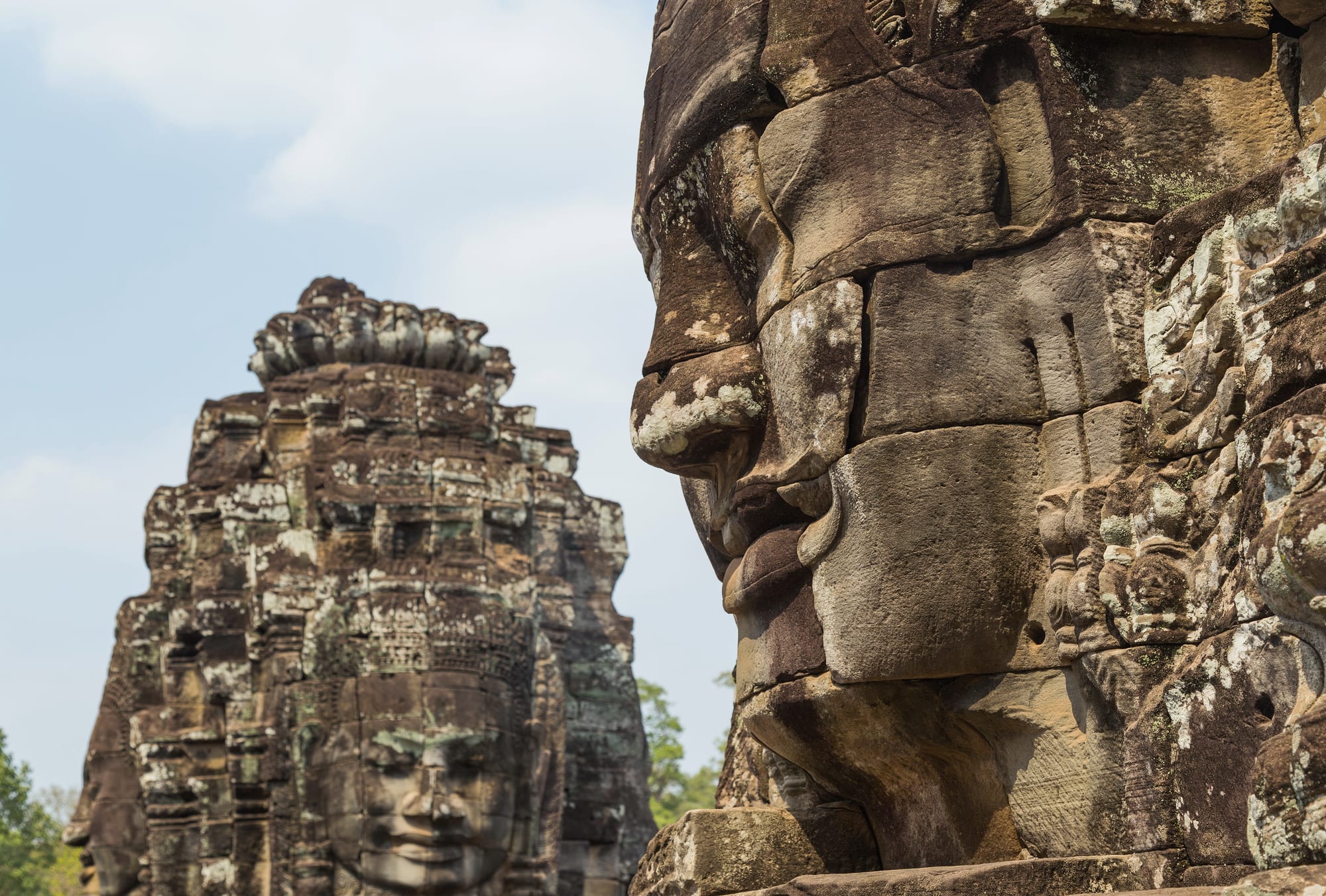 Stone towers each carved with four huge serene faces looking out in every direction, above temple galleries