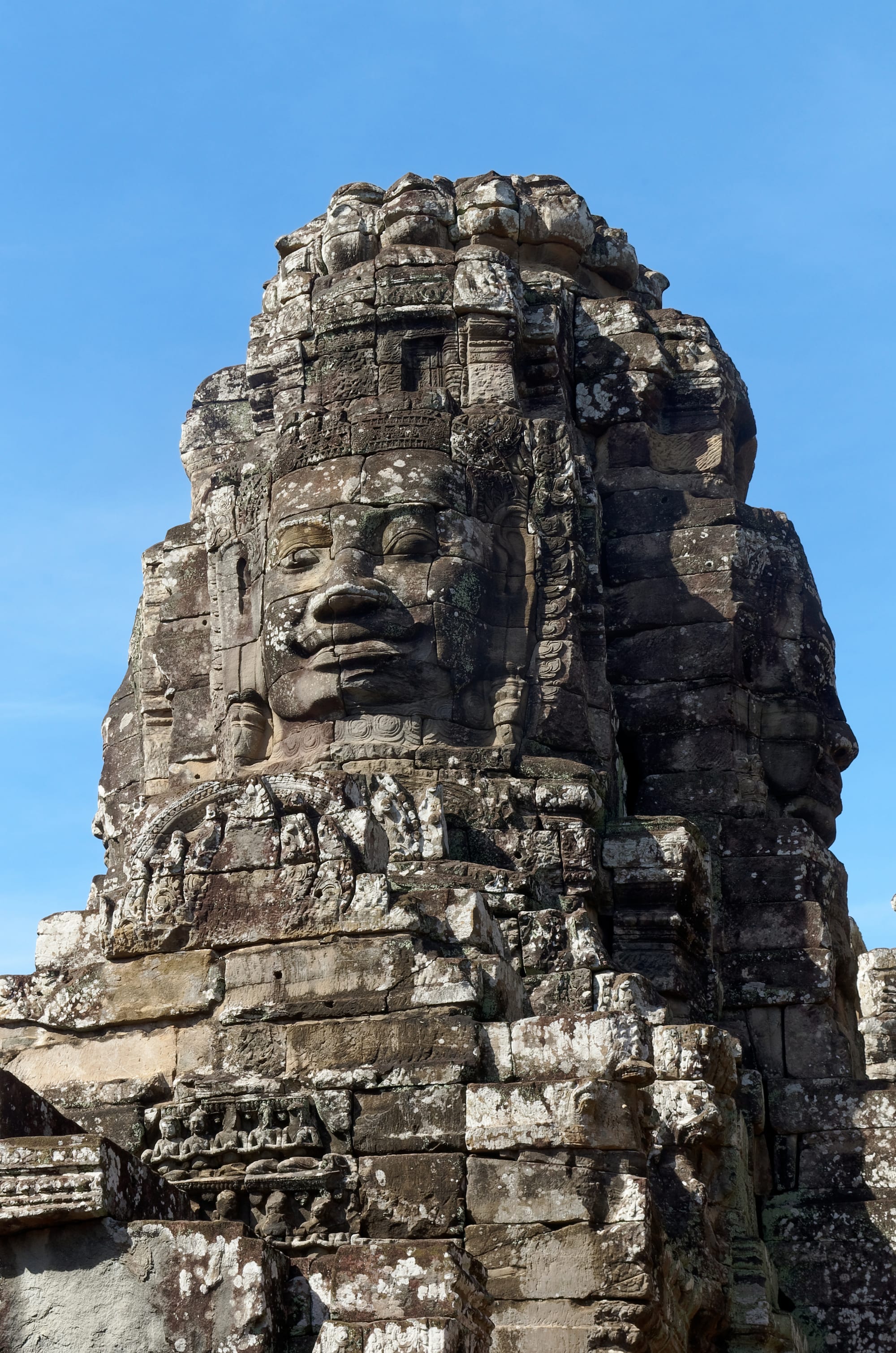 A temple of stacked towers, each carved with several enormous serene stone faces