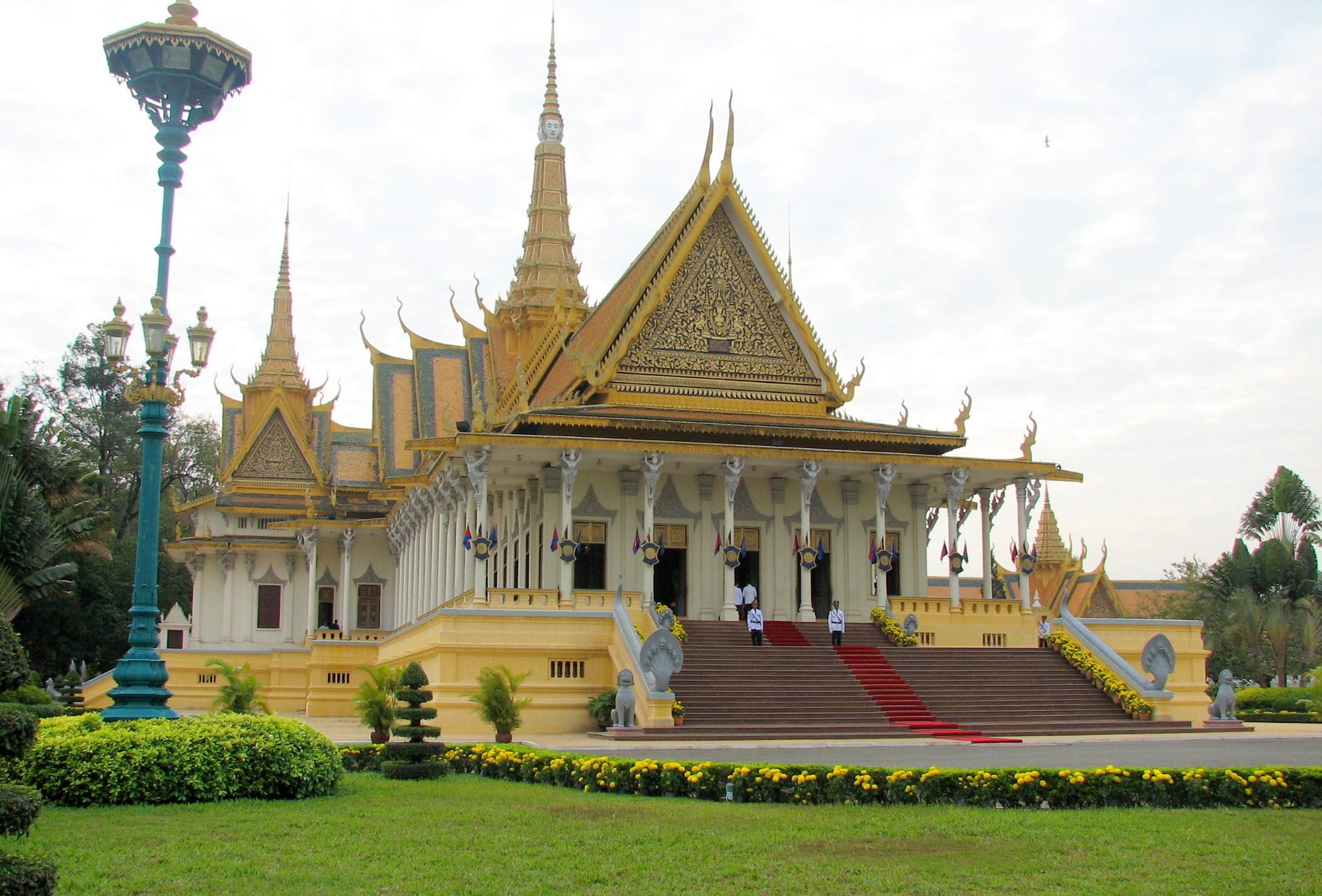 Golden-roofed pavilions with steep tiered rooftops and spires behind a yellow wall
