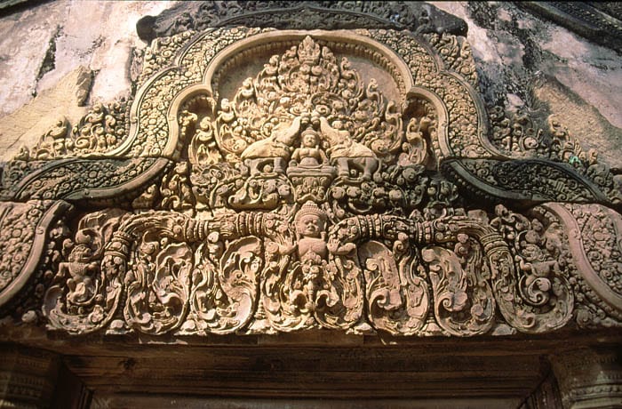 Small pink-sandstone temple towers covered in deep, intricate carving