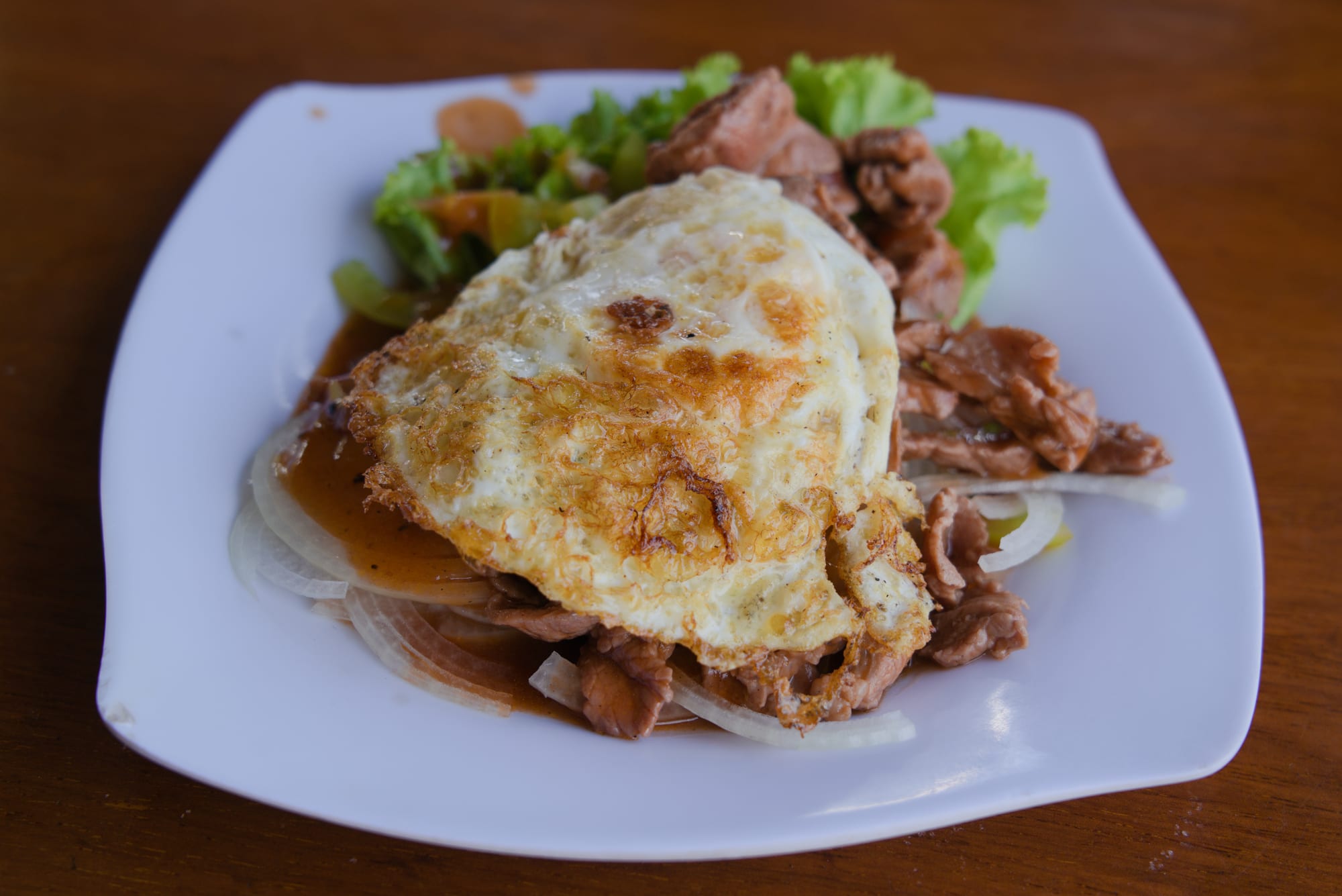 Stir-fried beef cubes served over lettuce and tomato with a dipping sauce