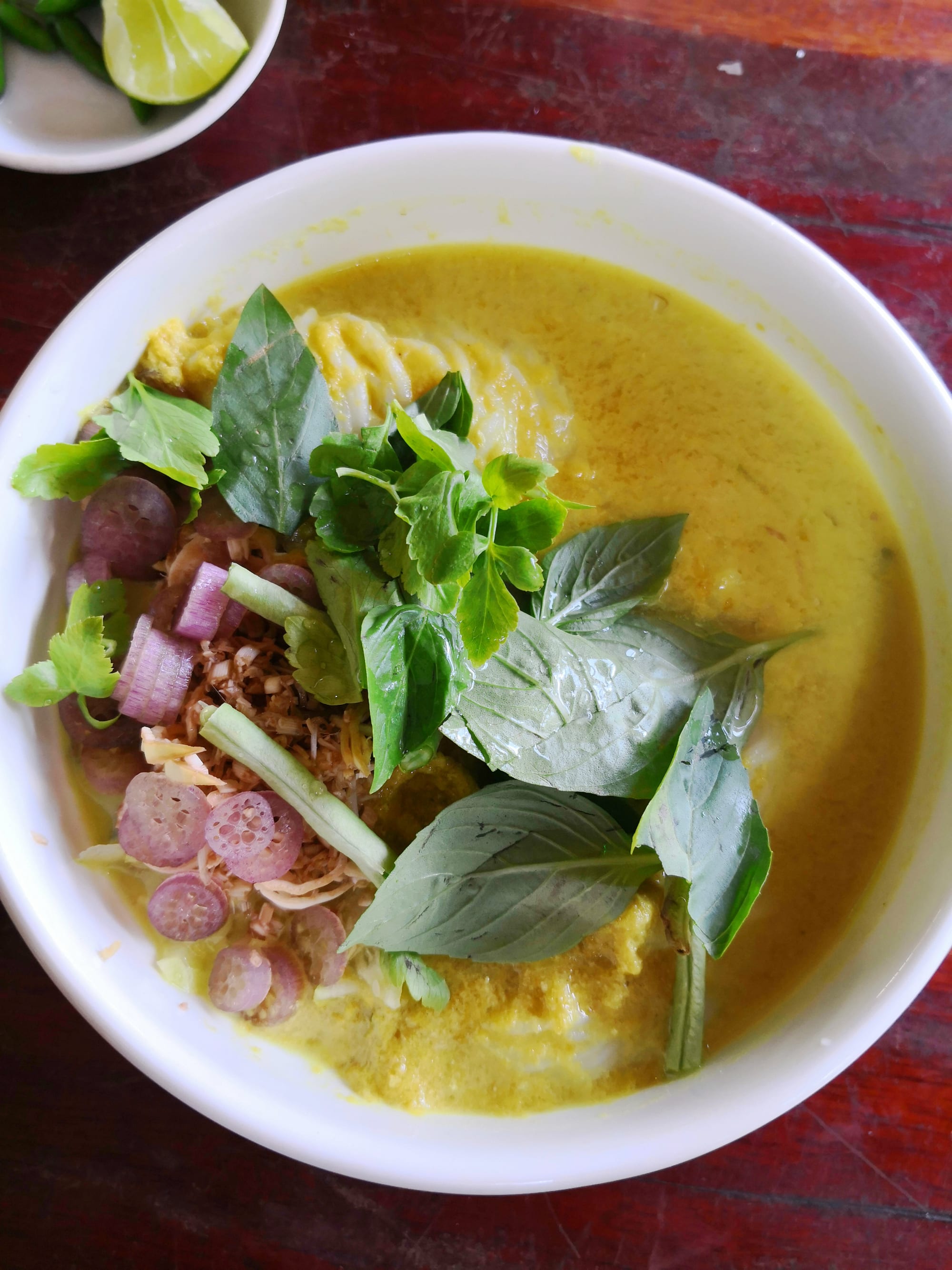 A plate of thin white rice noodles topped with a green herbed sauce and vegetables