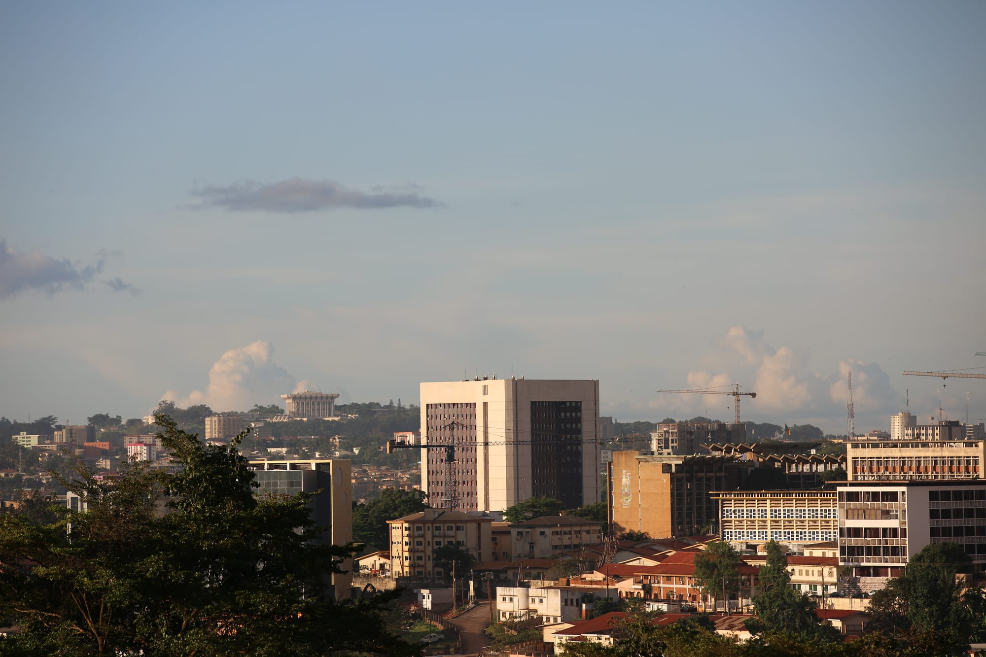 A modernist spiral monument and a wide city view of hills and low buildings