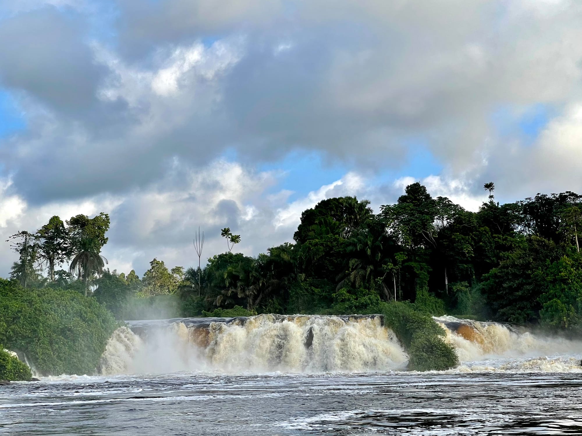 A wide river breaking into white cascades that flow directly onto a beach and into the sea