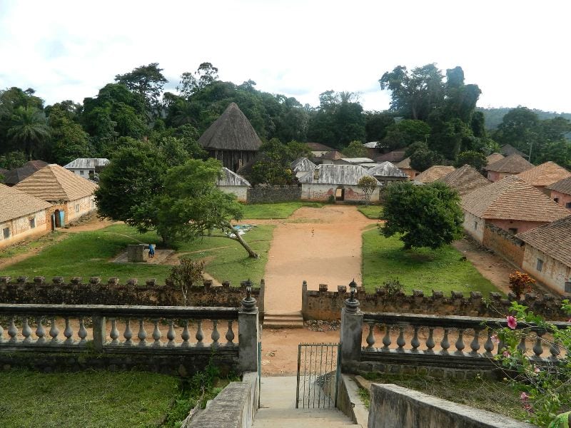 A large thatched conical shrine building among trees in a walled compound