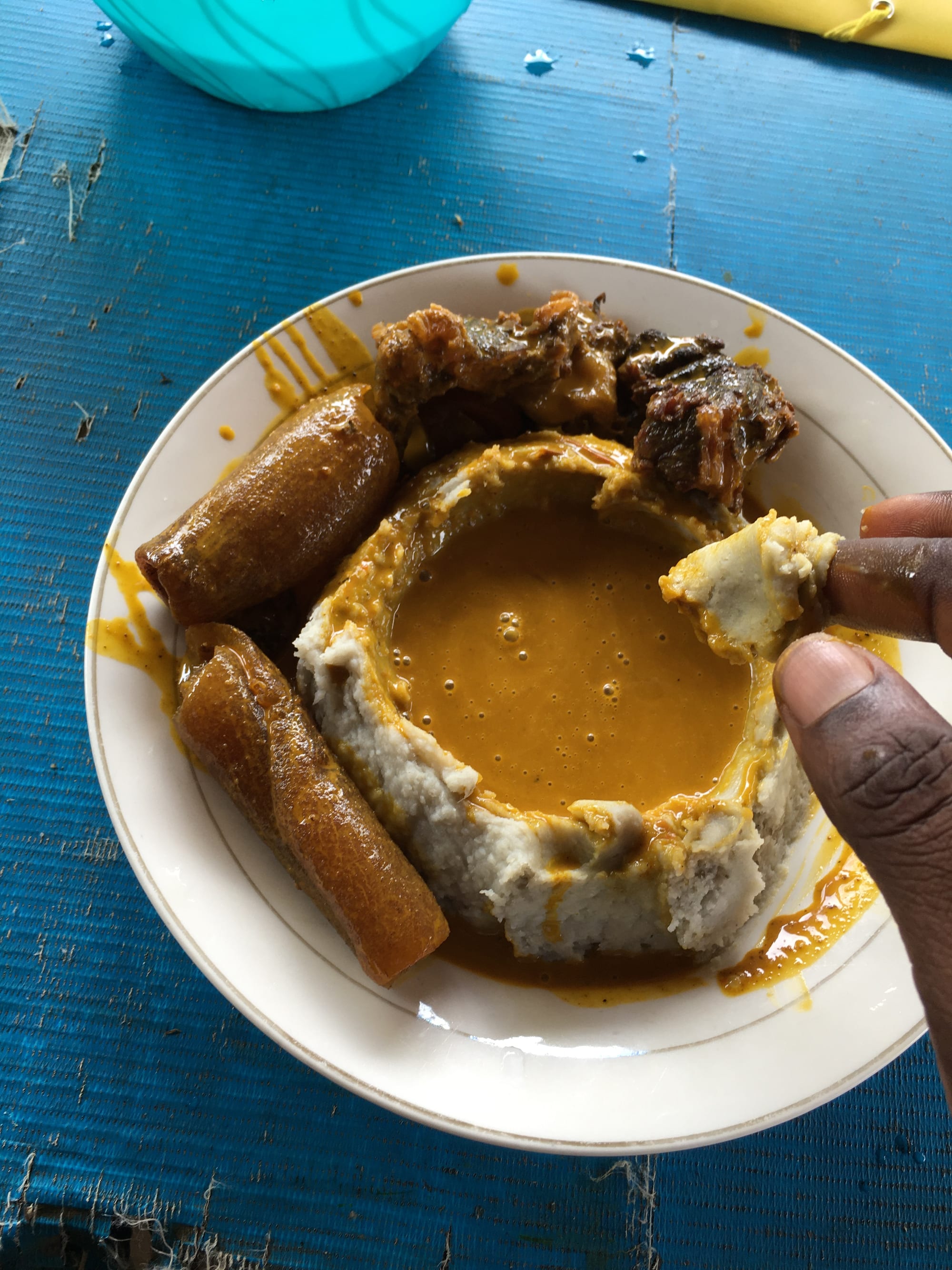 A mound of pale pounded cocoyam beside a bowl of vivid yellow soup