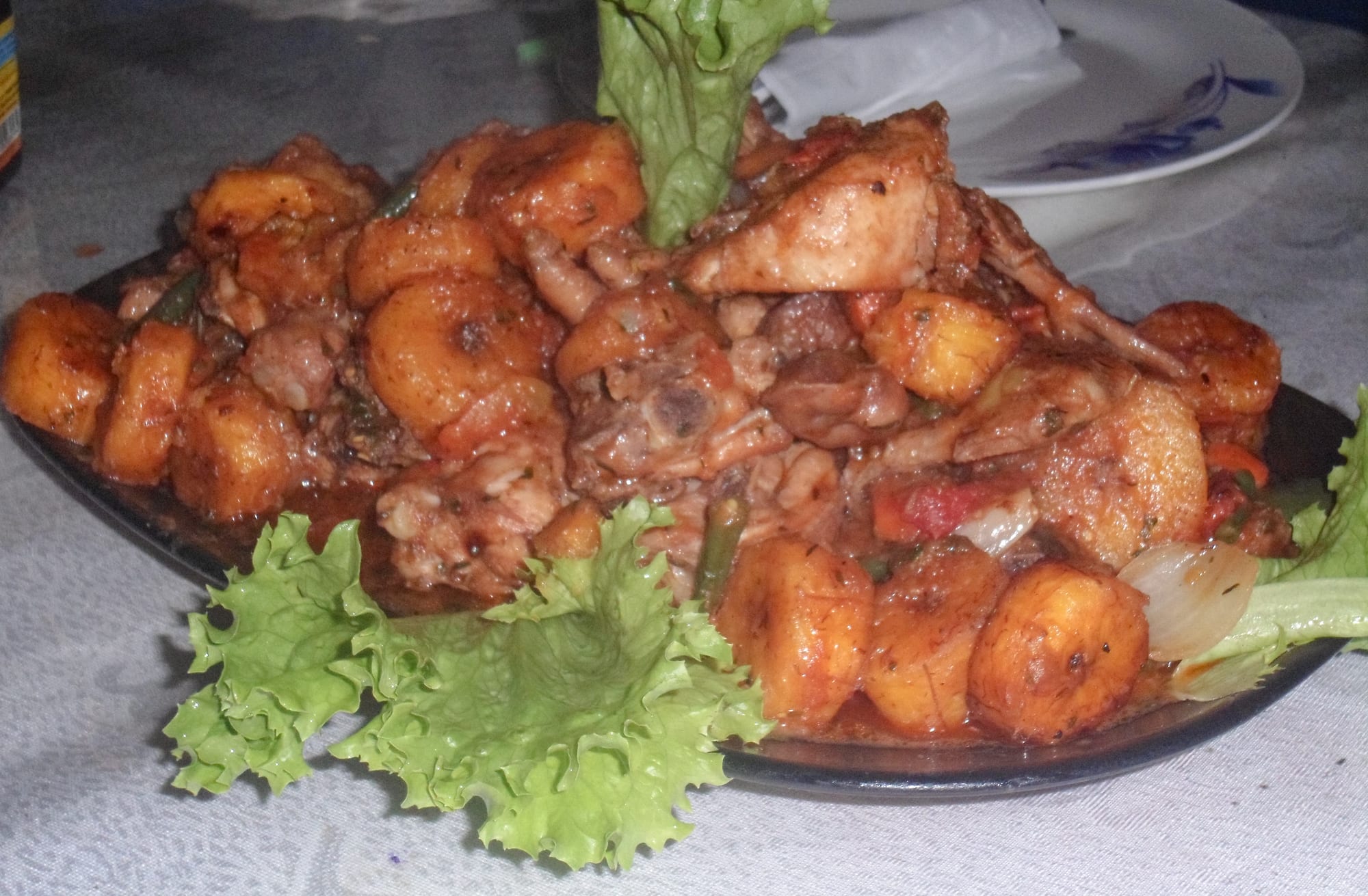 A plate of fried chicken pieces mixed with fried plantain slices and vegetables