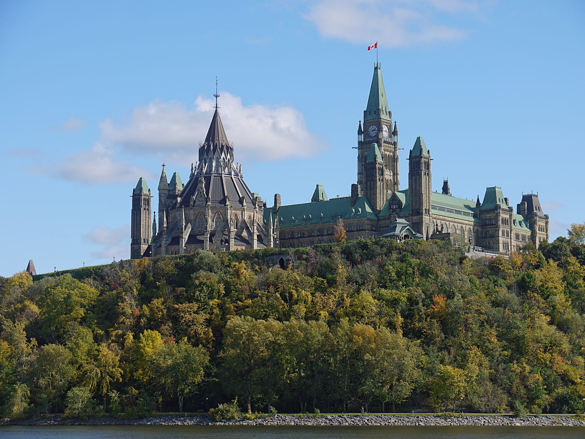 Gothic Revival government buildings with green copper roofs on a bluff above a river