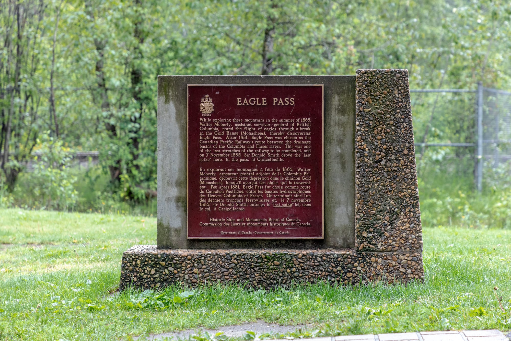 A memorial cairn and rail siding in a wooded mountain valley marking a historic spot