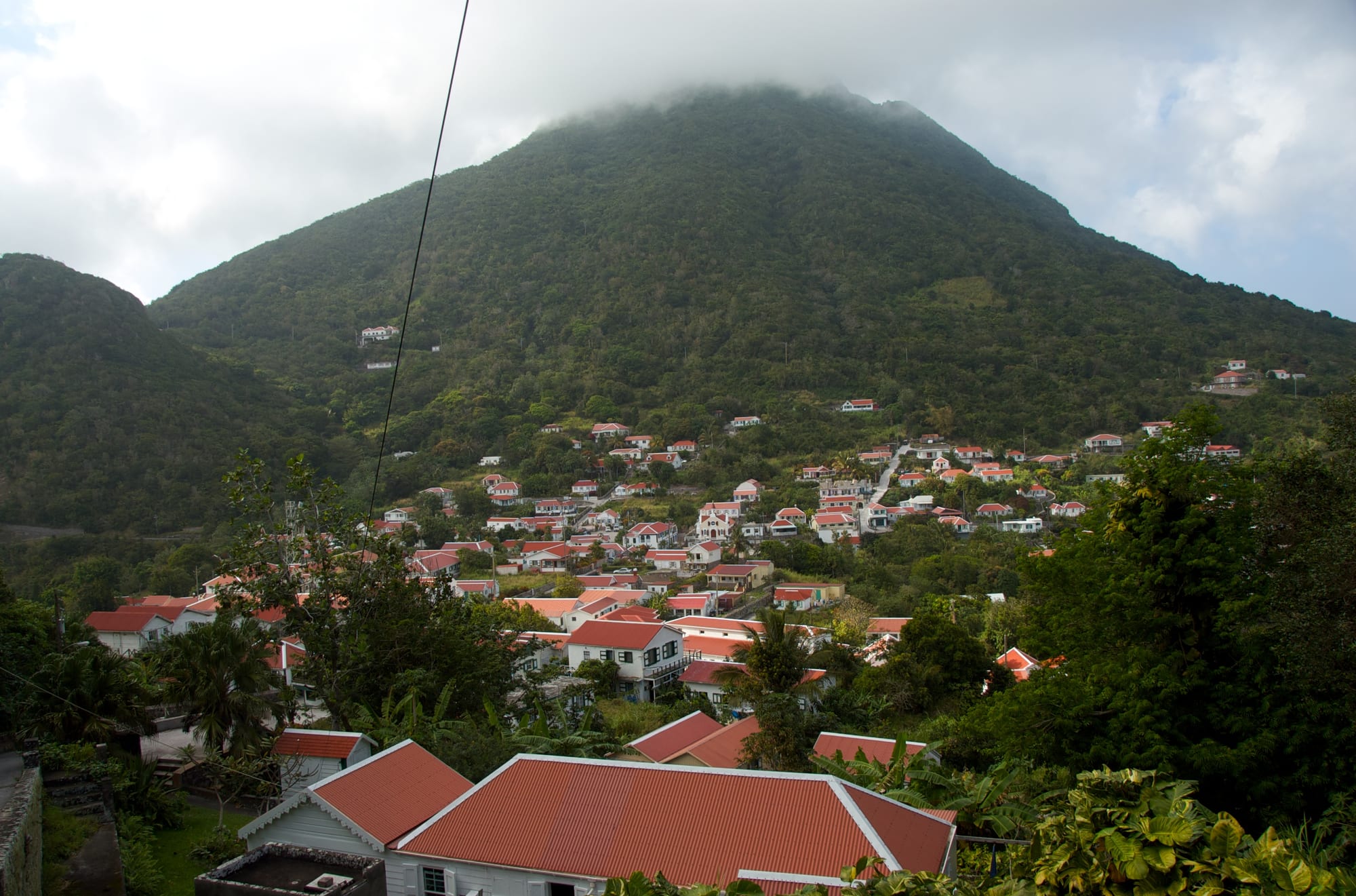 A steep green volcanic island with a tidy village of white cottages, the summit lost in cloud