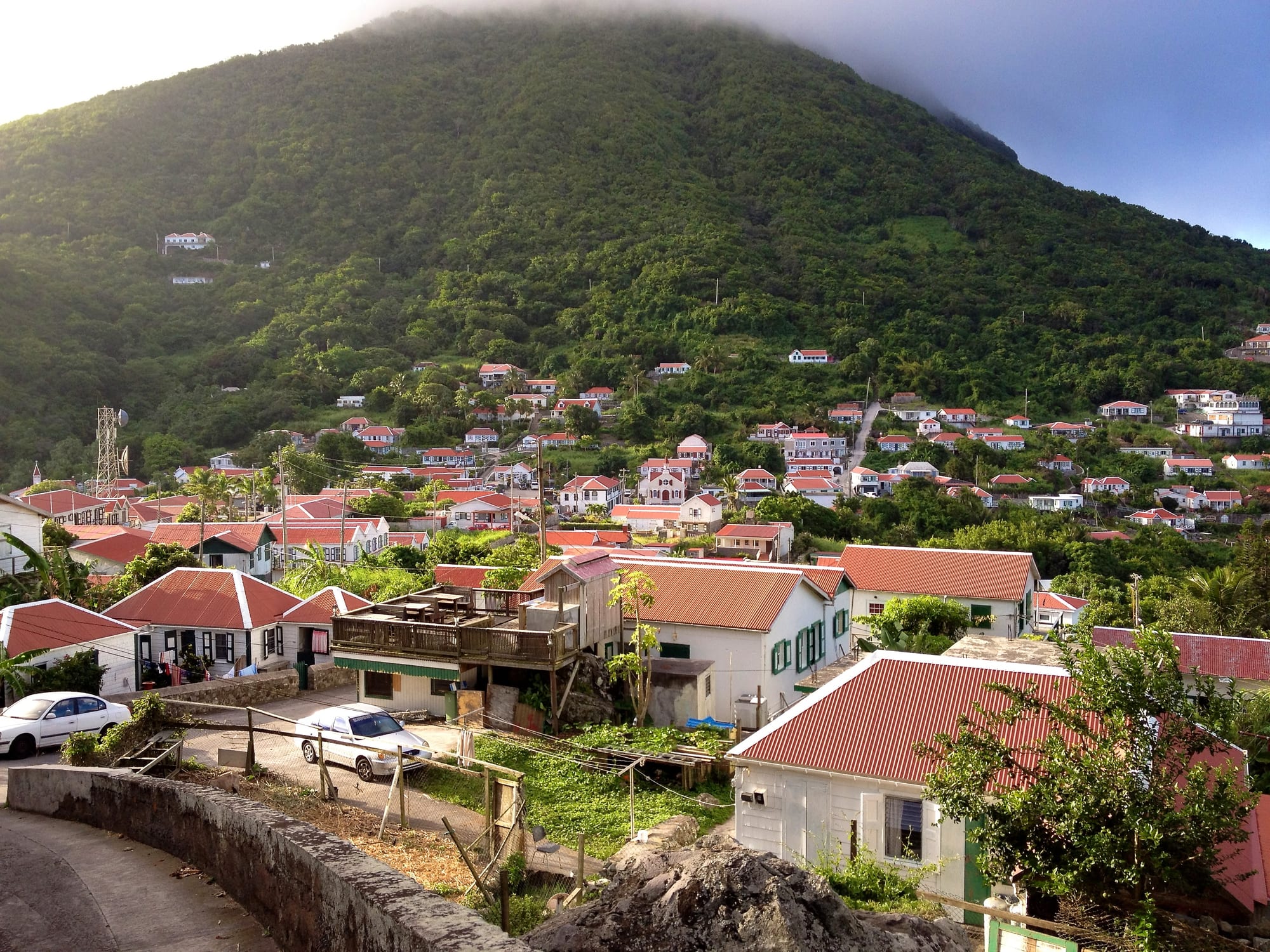 The village of Windwardside, red-roofed white houses climbing a green volcanic slope on Saba, with cloud covering the peak above