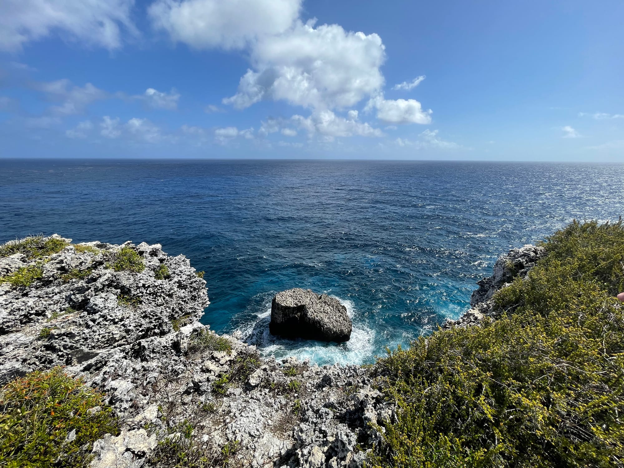 A low green island and a channel of blue sea seen from a limestone bluff