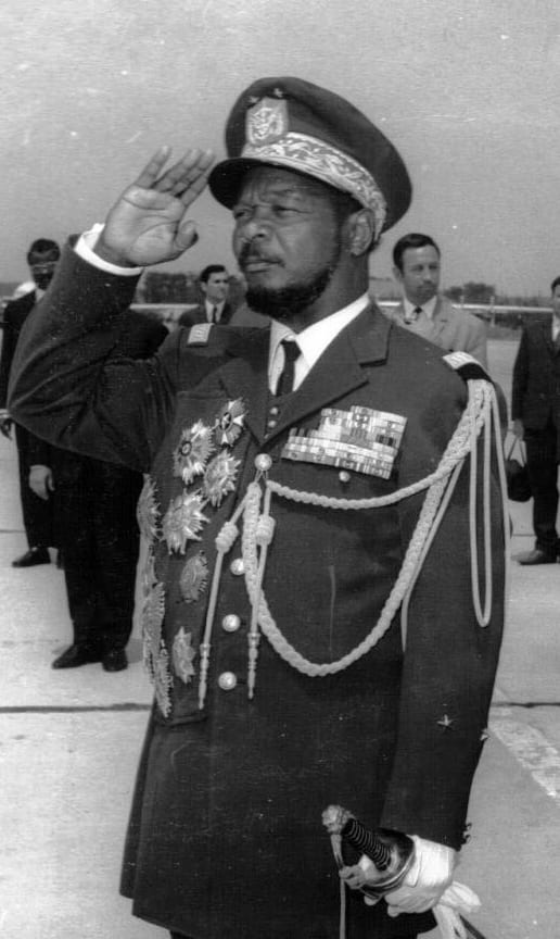 Bokassa in an ornate military uniform with heavy braid and medals, standing beside another head of state