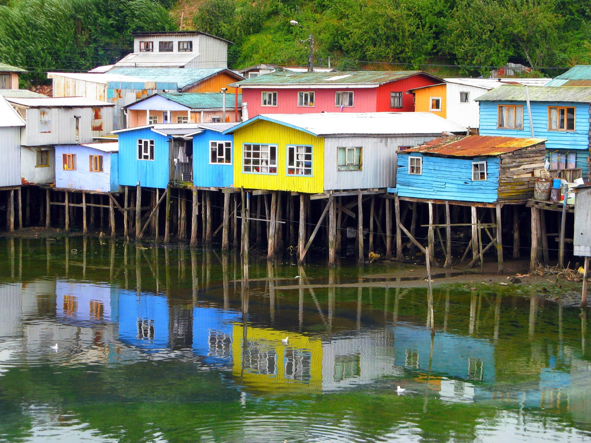 Wooden stilt houses painted in bright colours standing over the water on an inlet