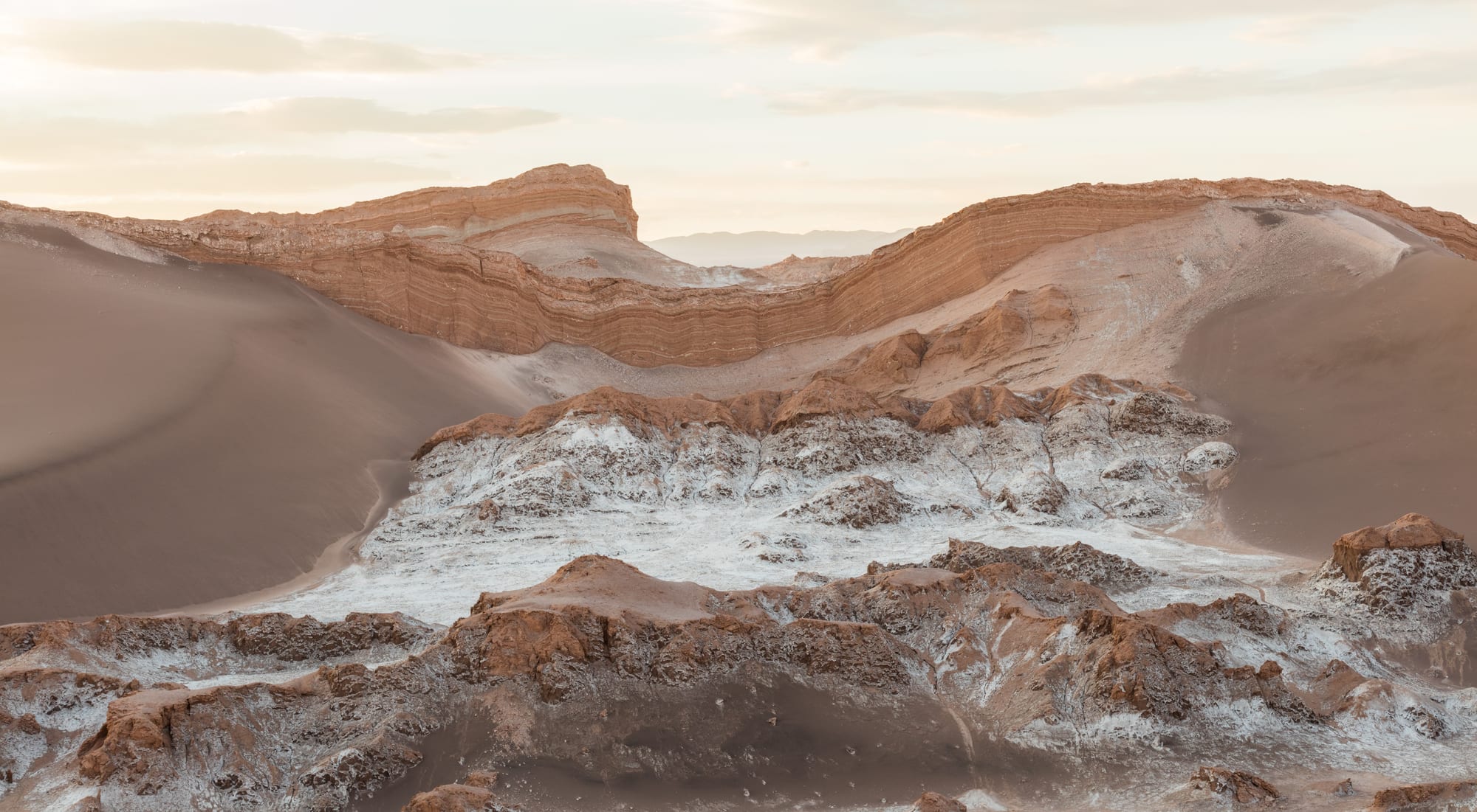 Sculpted ridges and salt-crusted hollows of a pale desert valley at low sun
