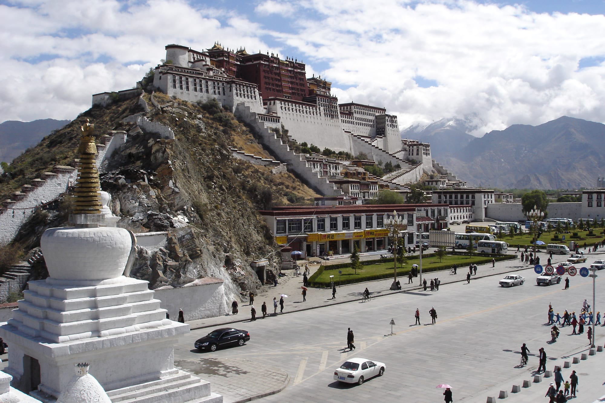 A massive white-and-red fortress-palace rising in tiers up a hill above a town