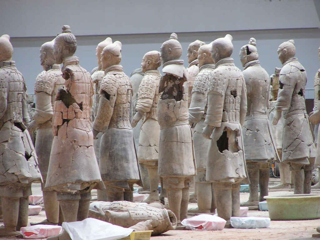 Rows of life-size clay soldiers standing in excavated earthen trenches