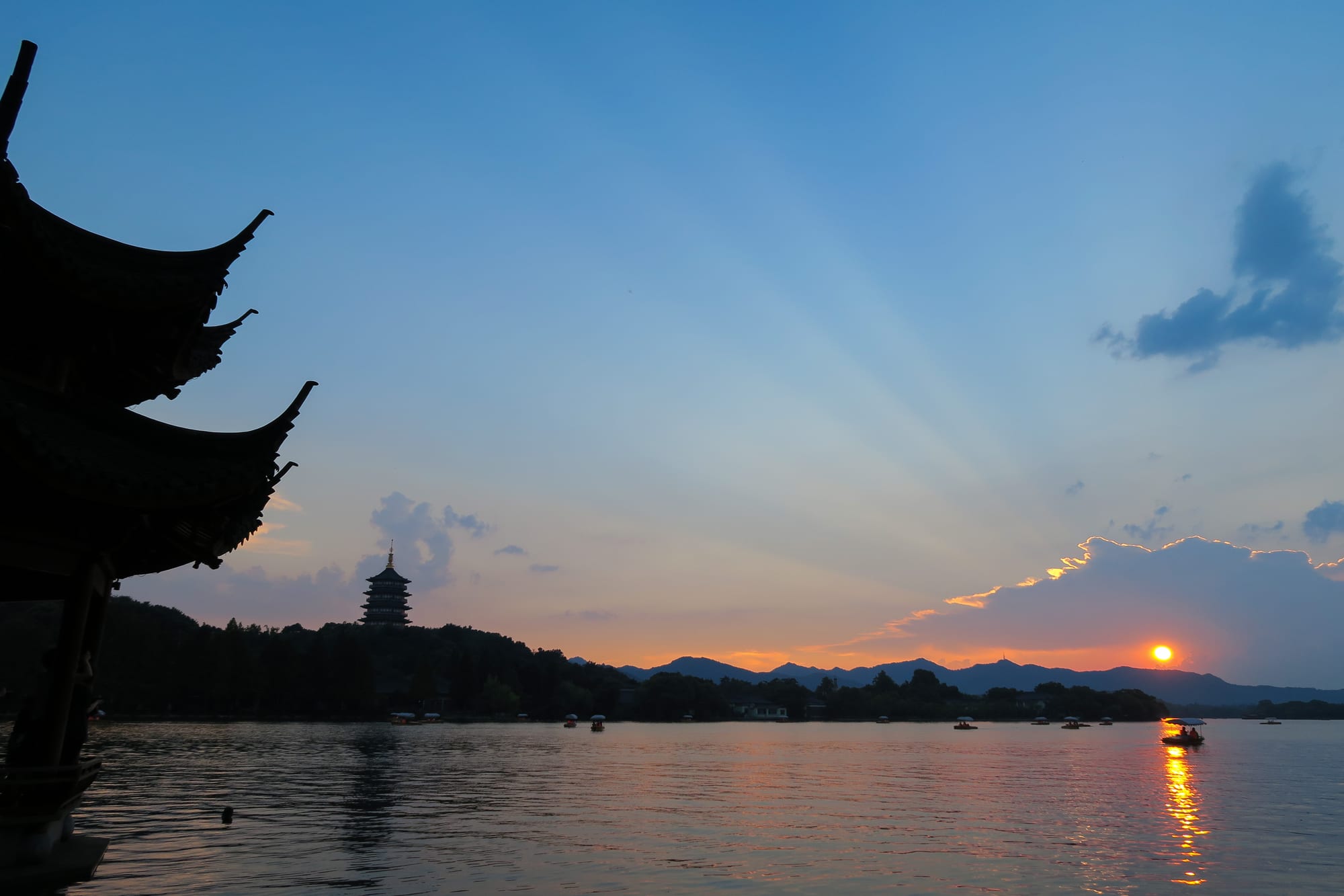 A pagoda silhouetted against a colourful sunset over a calm lake