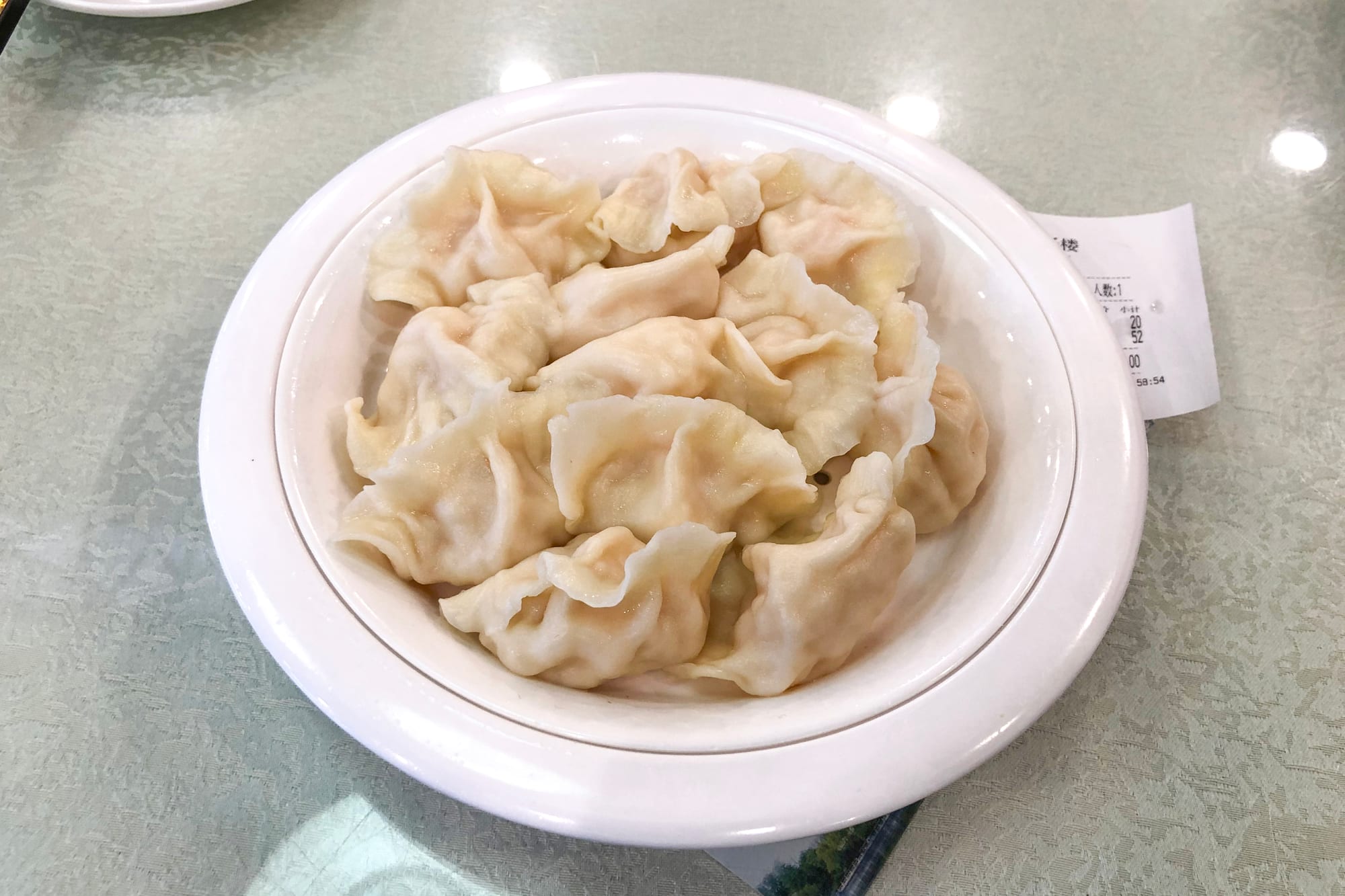 A plate of boiled dumplings with visible pleated edges