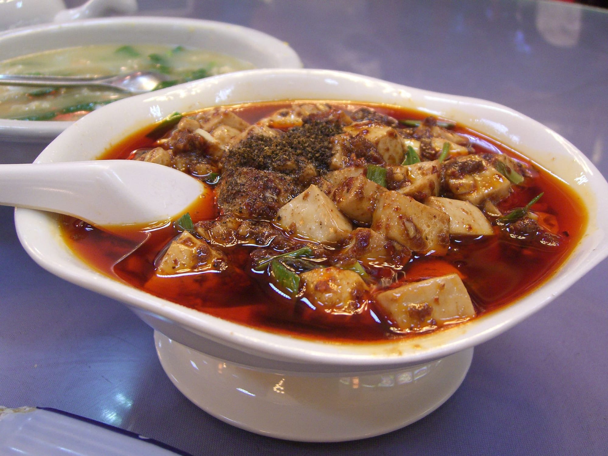 A dish of soft tofu cubes in a red, oily chilli sauce with visible ground meat