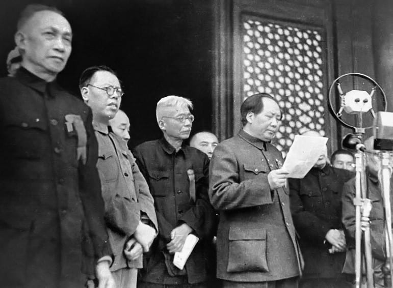 Mao Zedong at a microphone on a rostrum above a gate, reading a proclamation, 1949