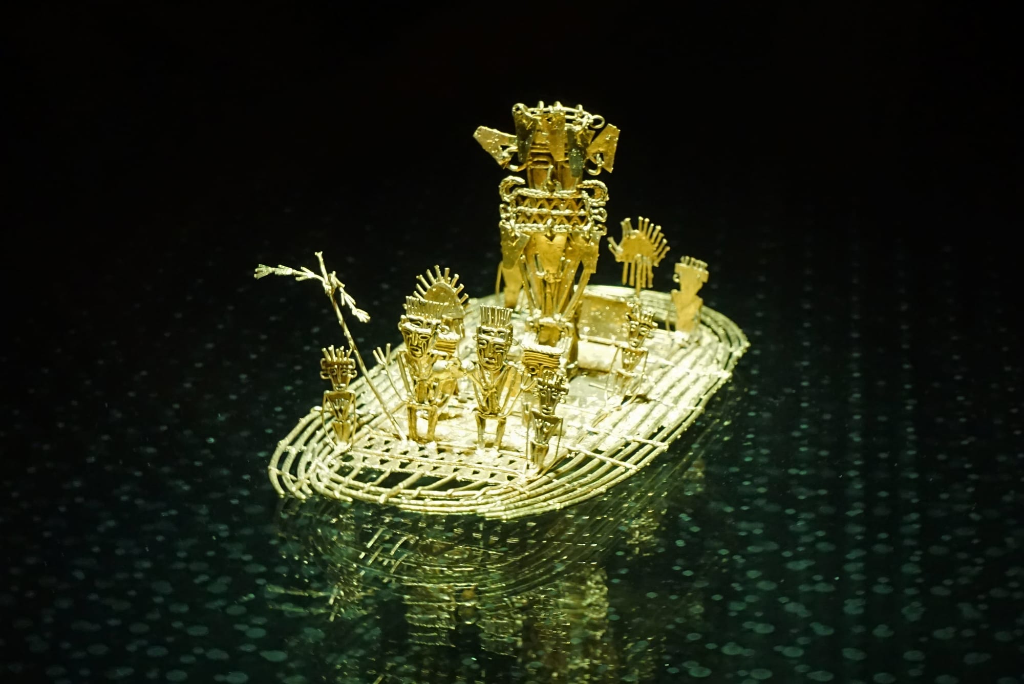 A small golden figure group on a raft, cast in one piece, a chief surrounded by attendants