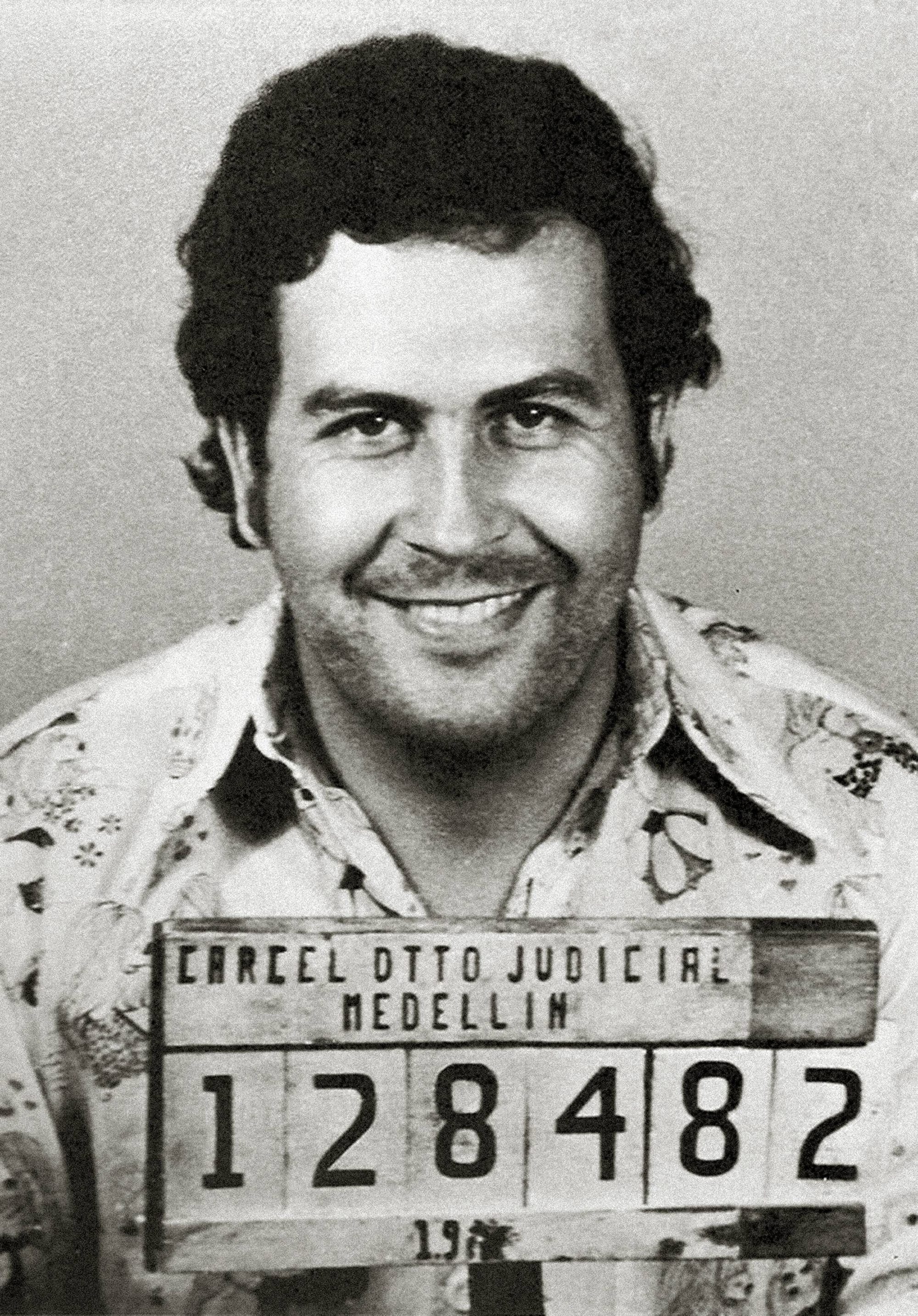 A 1970s police mugshot of Pablo Escobar, a heavyset man with dark hair, half-smiling