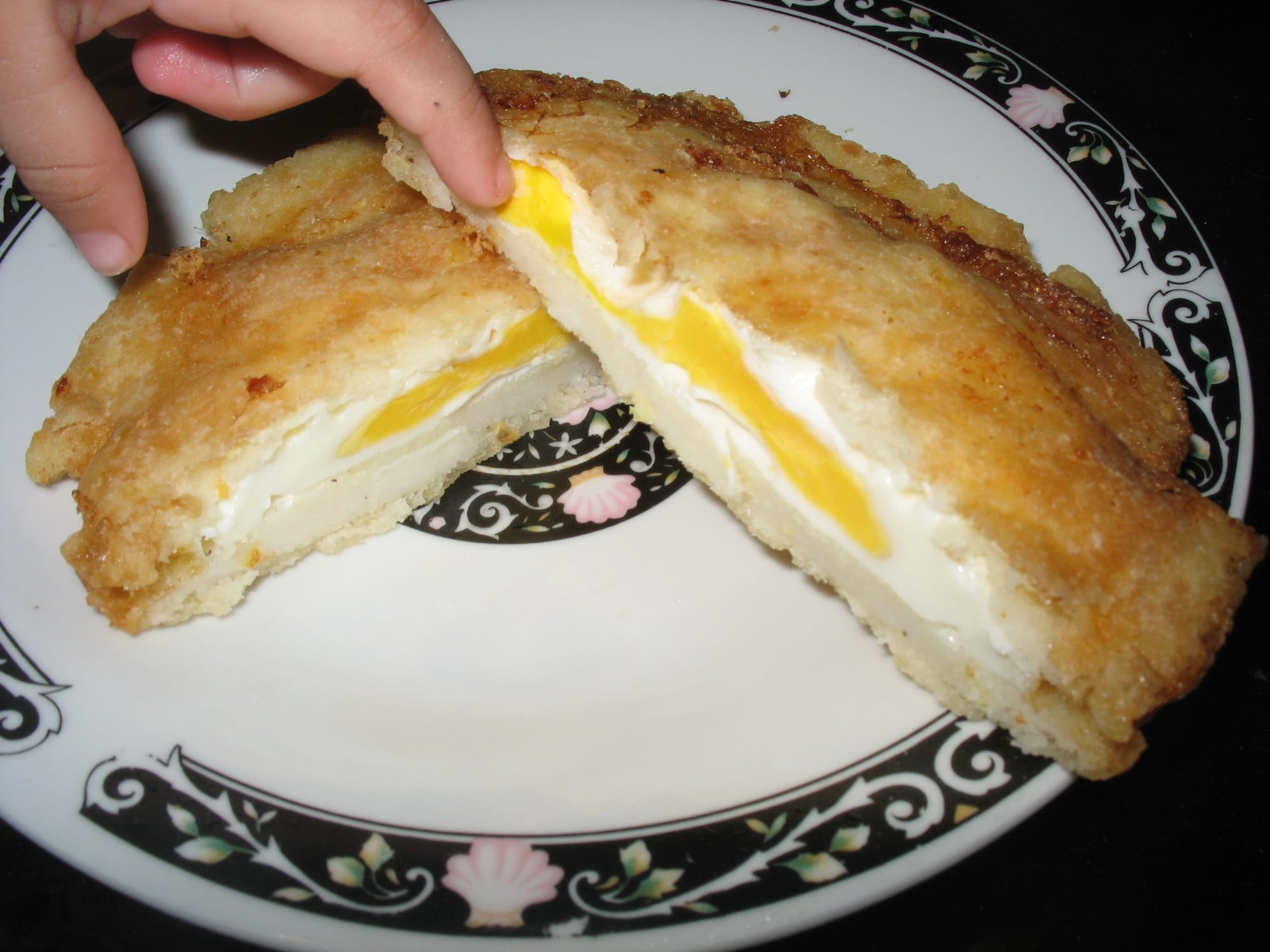 A cross-section of a fried corn cake showing a whole cooked egg inside