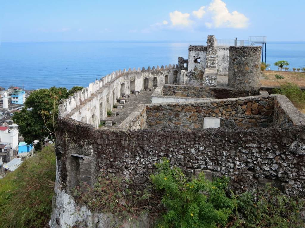 Thick stone fortress walls with bastions on a rise above a dense old town