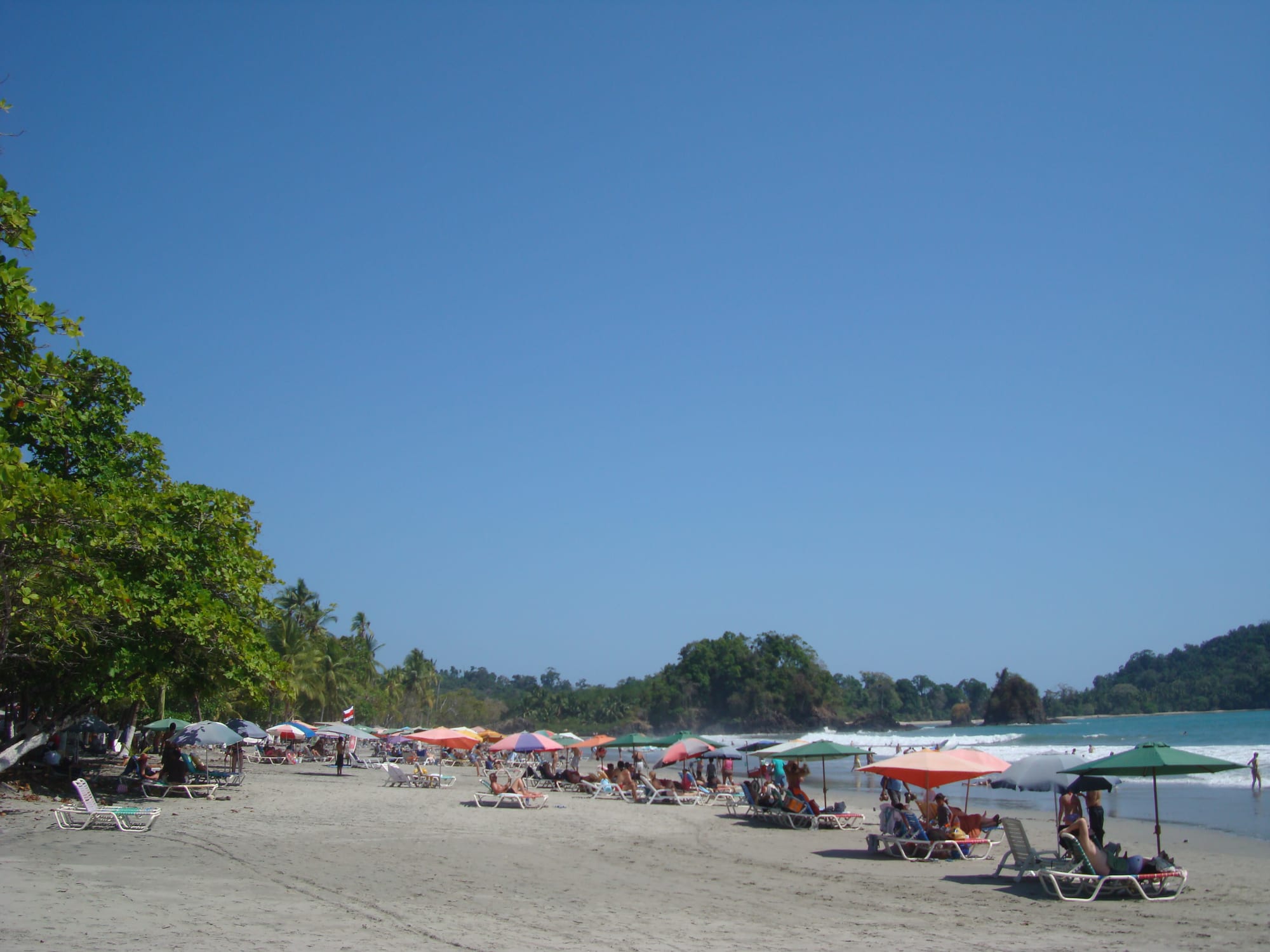 A curved white-sand beach backed by dense rainforest and a rocky headland