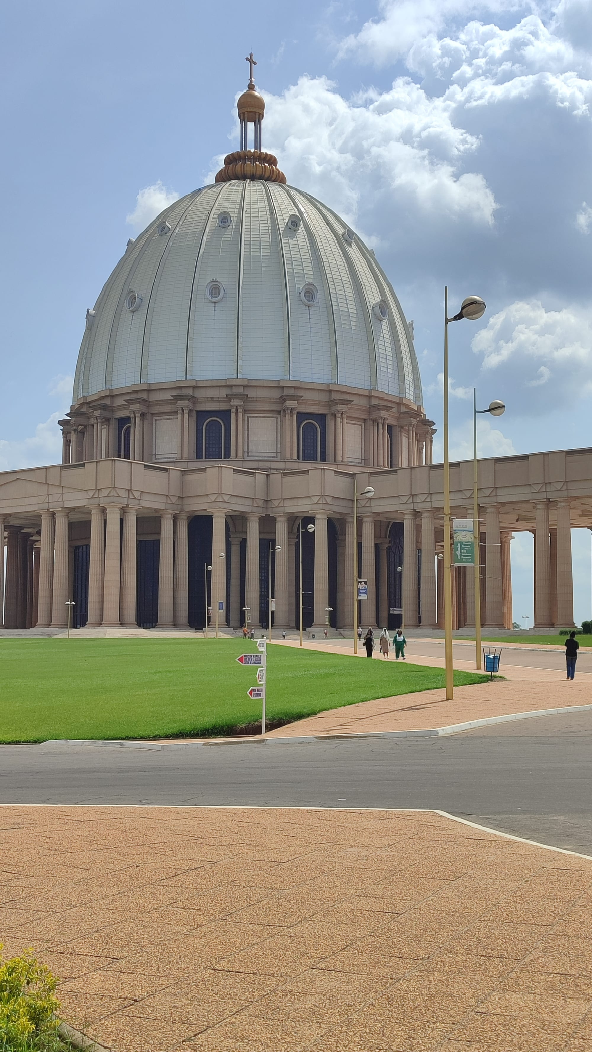 An enormous domed basilica with a colonnaded plaza, standing alone against a flat green landscape
