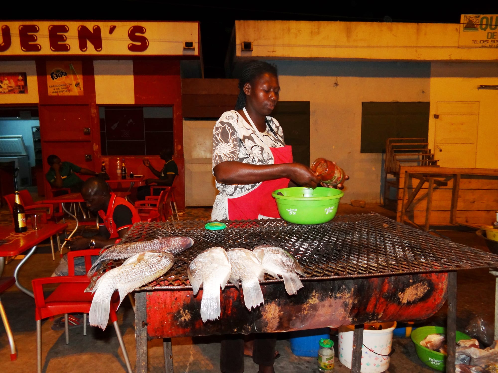 A person preparing grilled fish and fermented cassava couscous