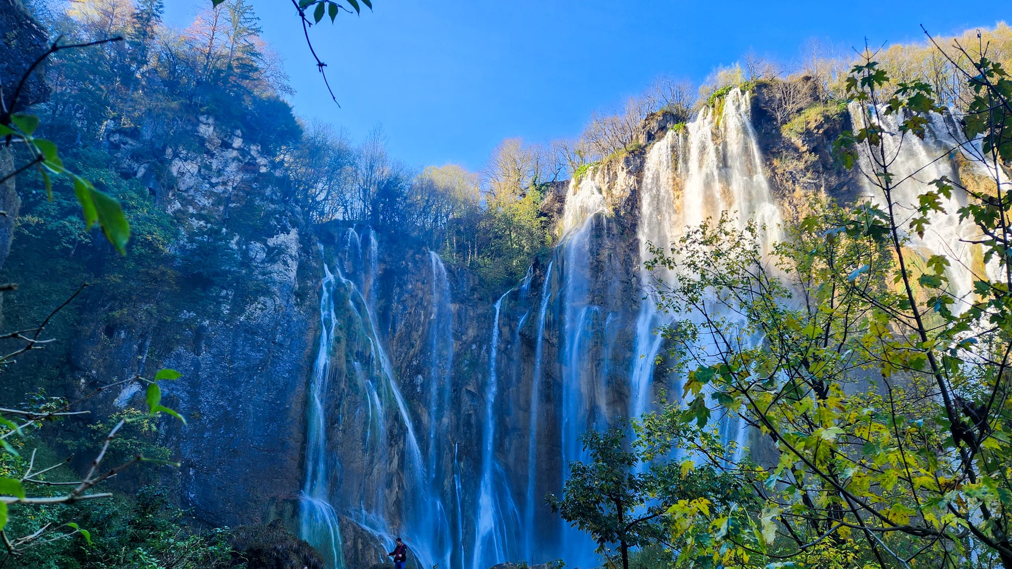 Turquoise lakes on different levels linked by dozens of white waterfalls, forest all around