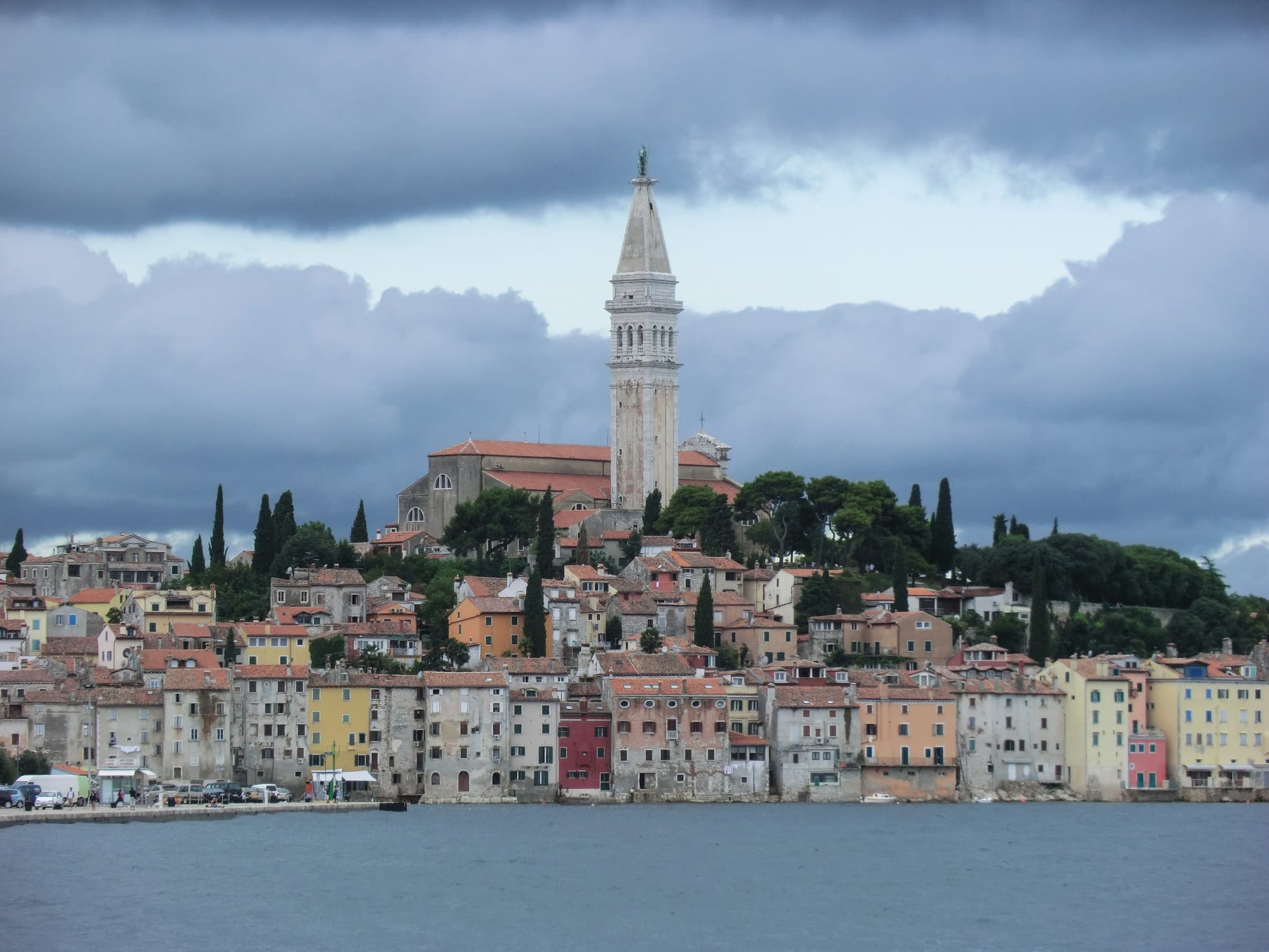 A cluster of pastel houses on a small peninsula rising to a tall church bell tower