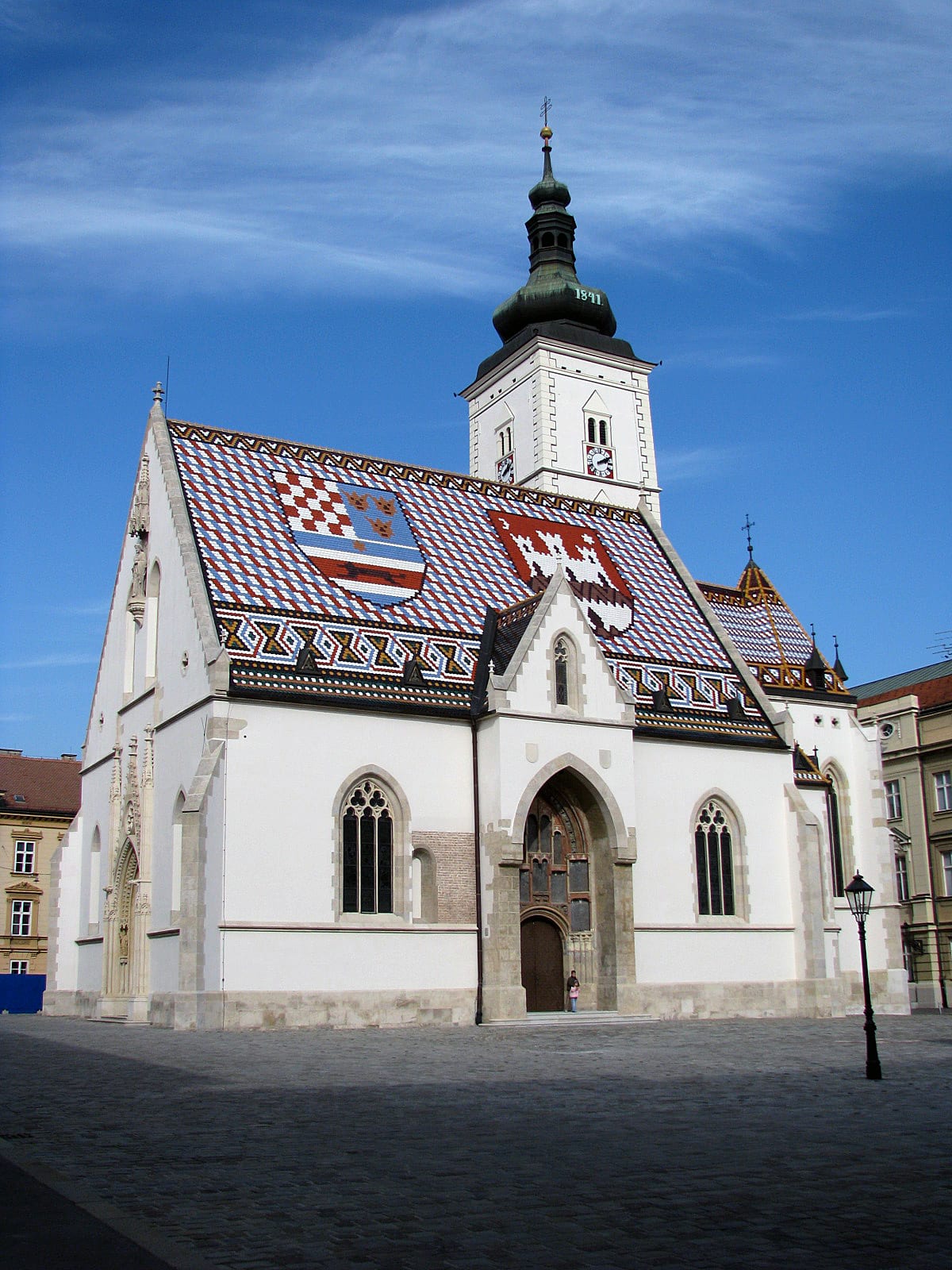 A church with a steep tiled roof laid out in two coloured coats of arms